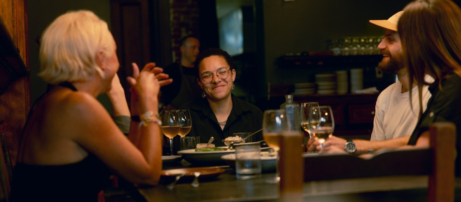 Friends talking over dinner and wine at a dimly lit restaurant.