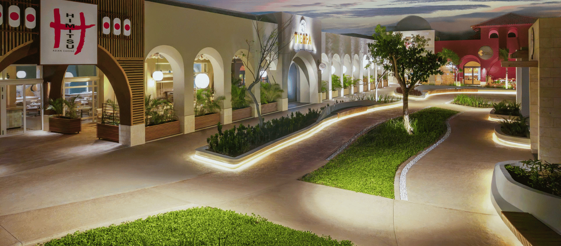Landscaped garden walkway with tropical greenery and evening lighting at Dreams Playa Esmeralda.