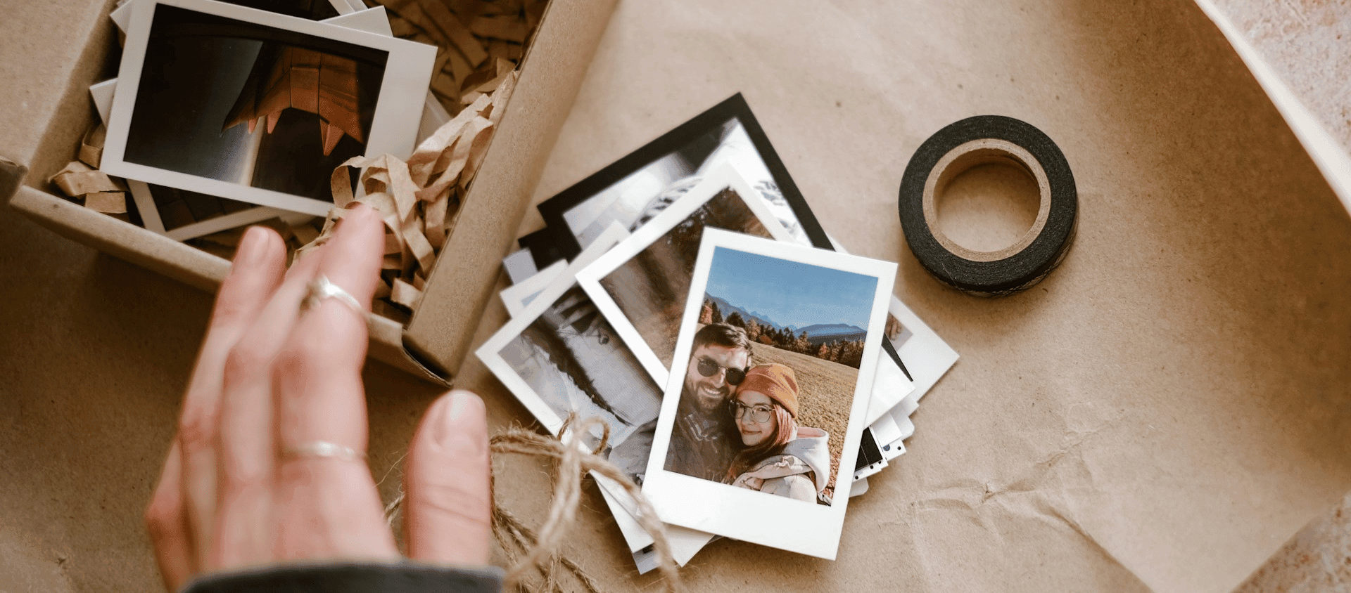 Stack of instant photos on a table with hands arranging them.