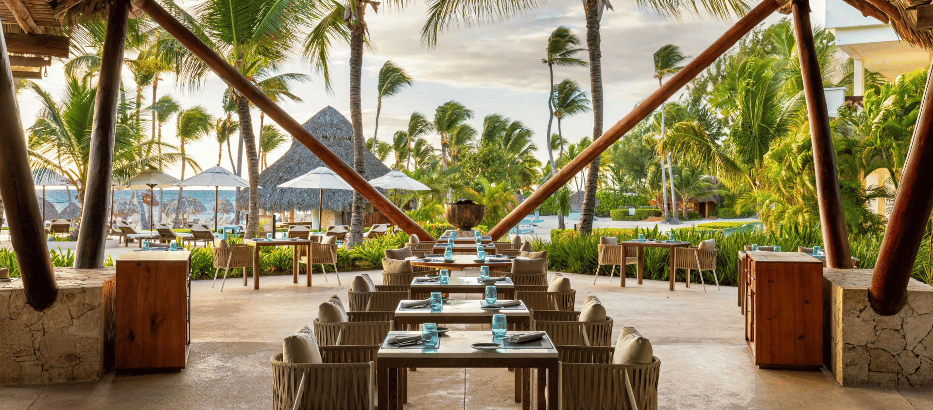 Open air beachfront restaurant with palm trees and outdoor seating at Secrets Cap Cana.
