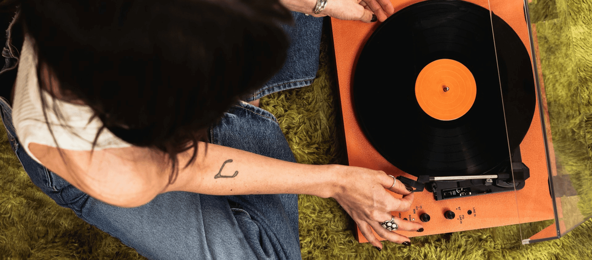 A woman sitting down playing a record player