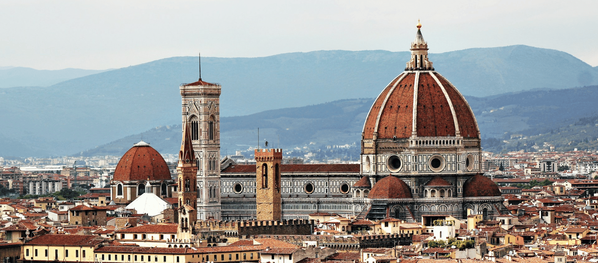 Panoramic view of Florence featuring the Duomo and city rooftops against a backdrop of rolling hills.