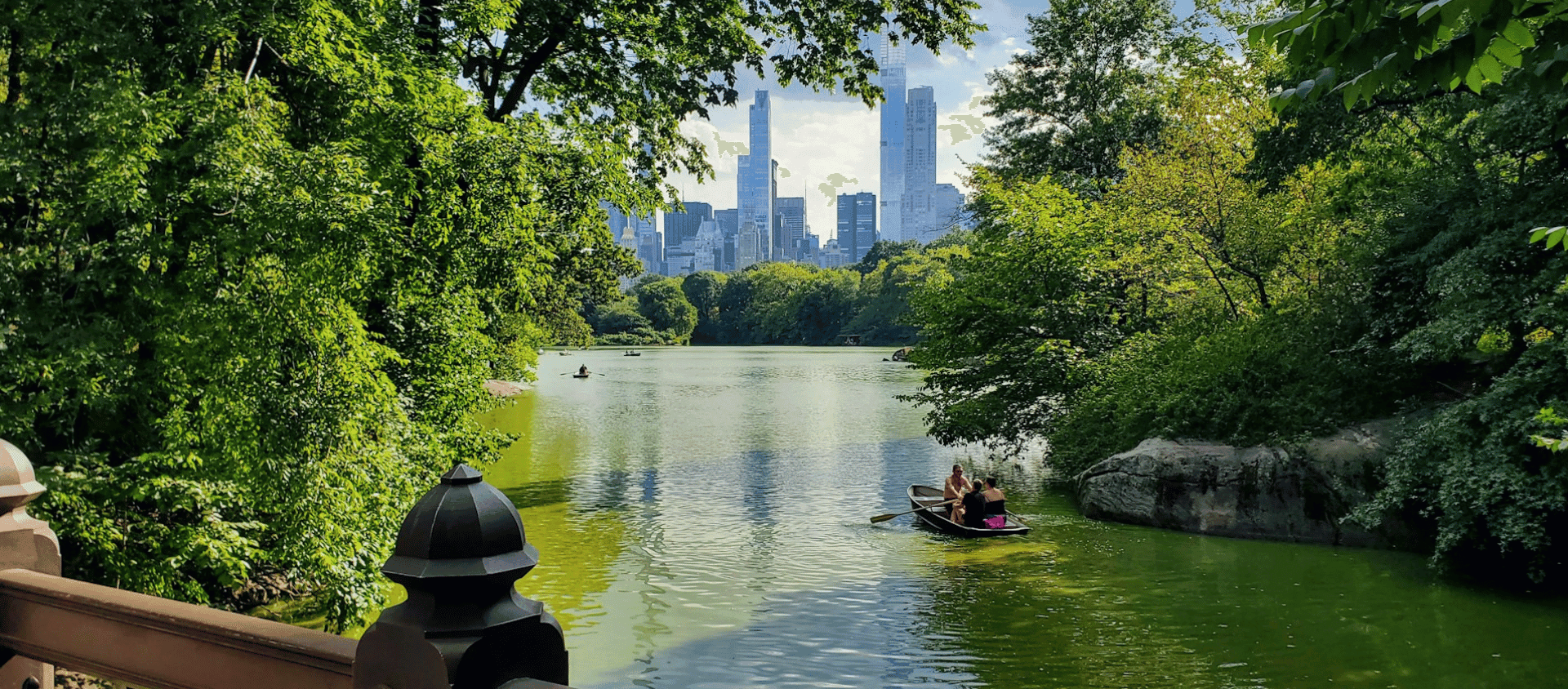 Rowboats on Central Park Lake with Manhattan skyline in the background.