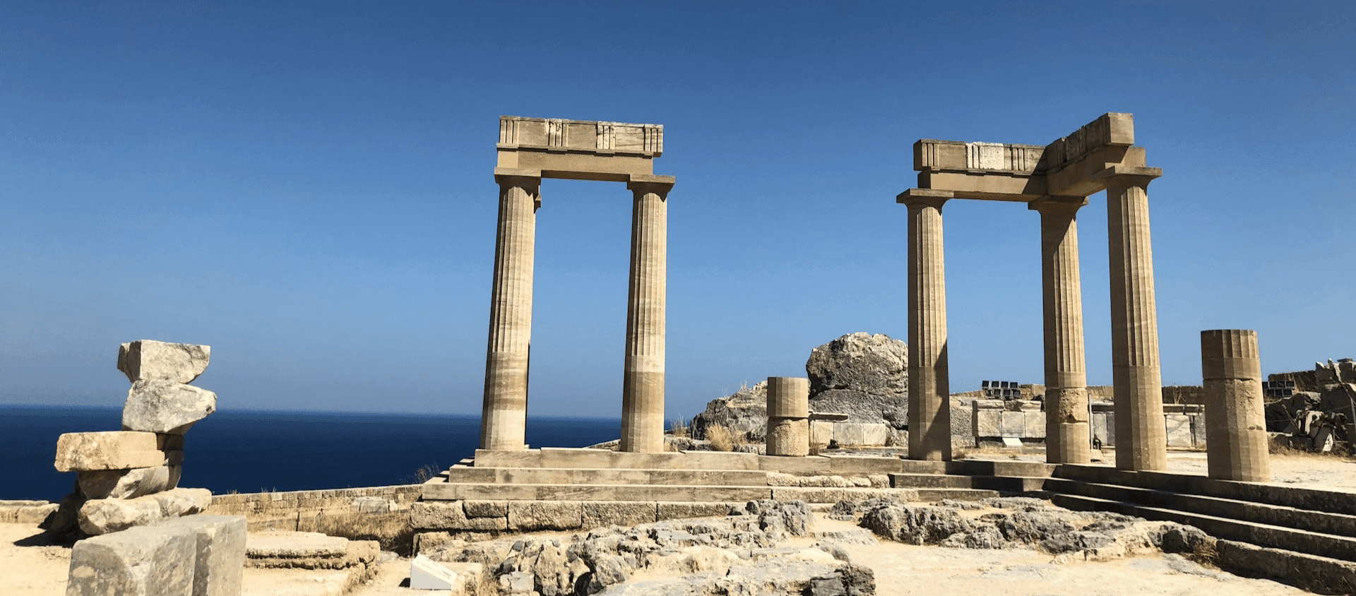 Ancient Greek columns at the Acropolis of Rhodes overlooking the sea.