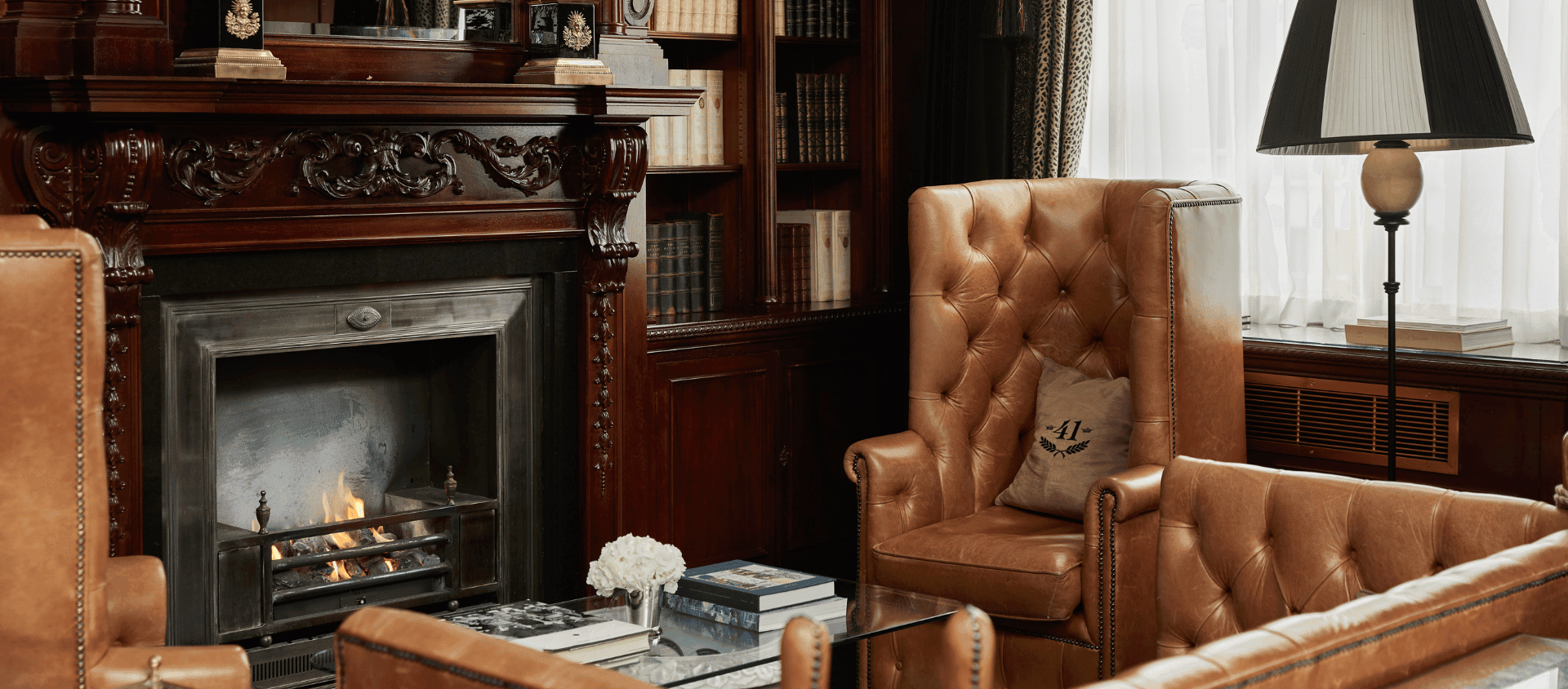 Hotel 41 library lounge with fireplace and leather armchairs.