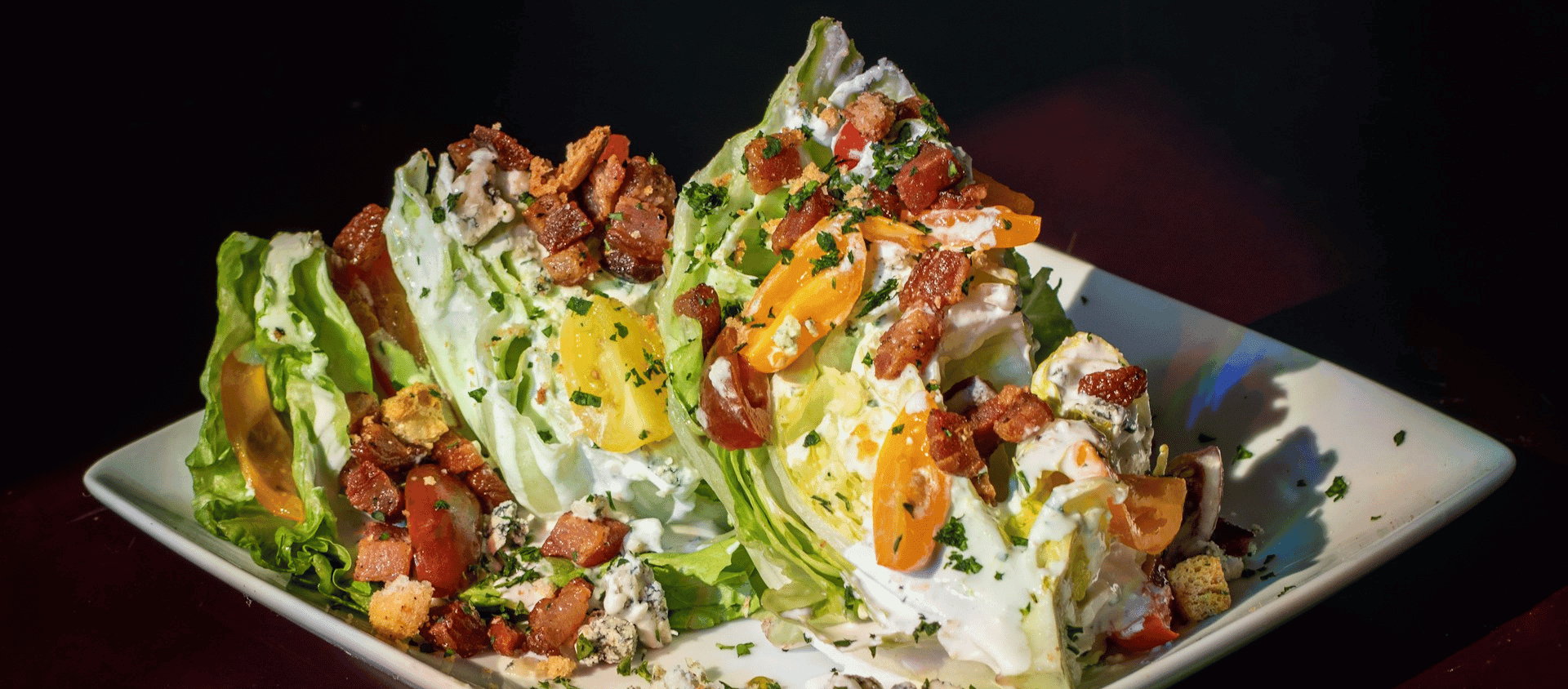 Iceberg wedge salad topped with bacon, tomatoes, and creamy dressing.