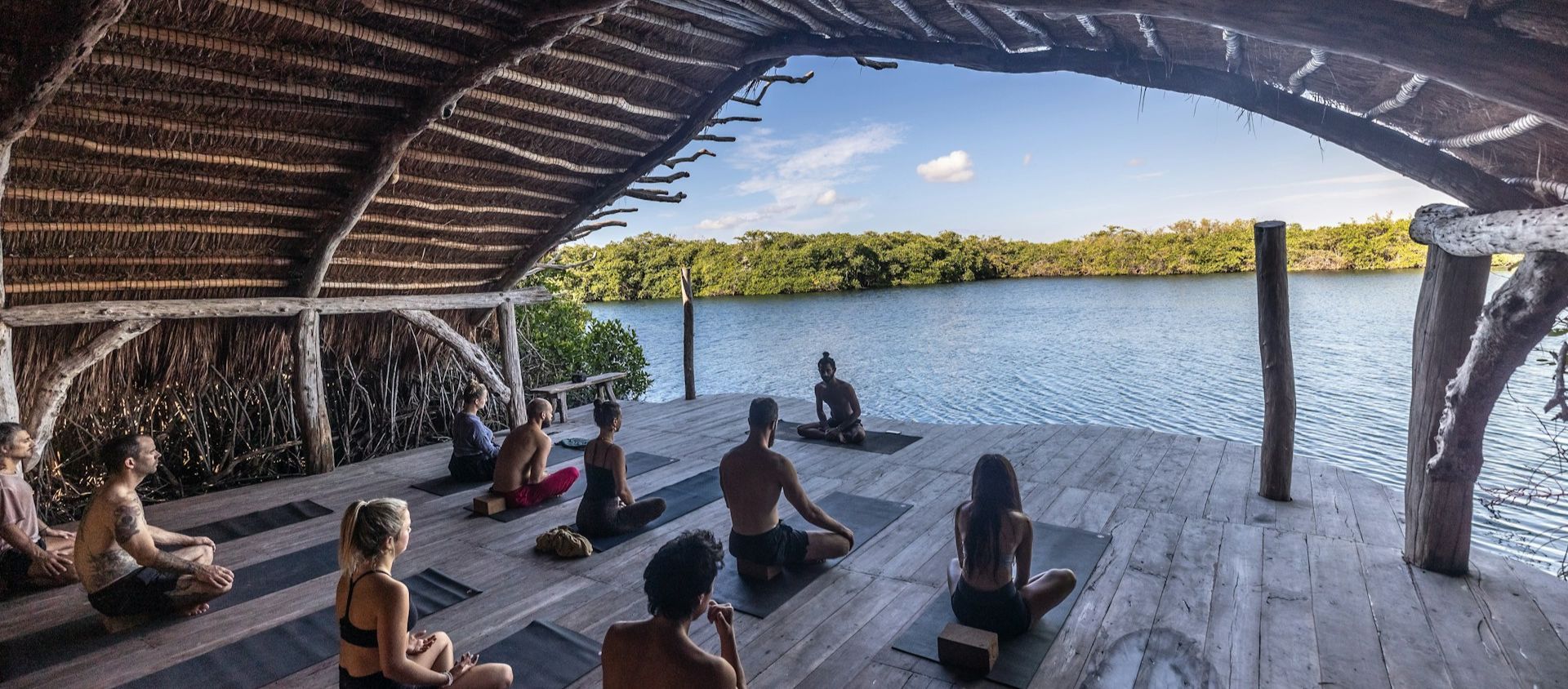 Group doing yoga on an open-air deck by the water.