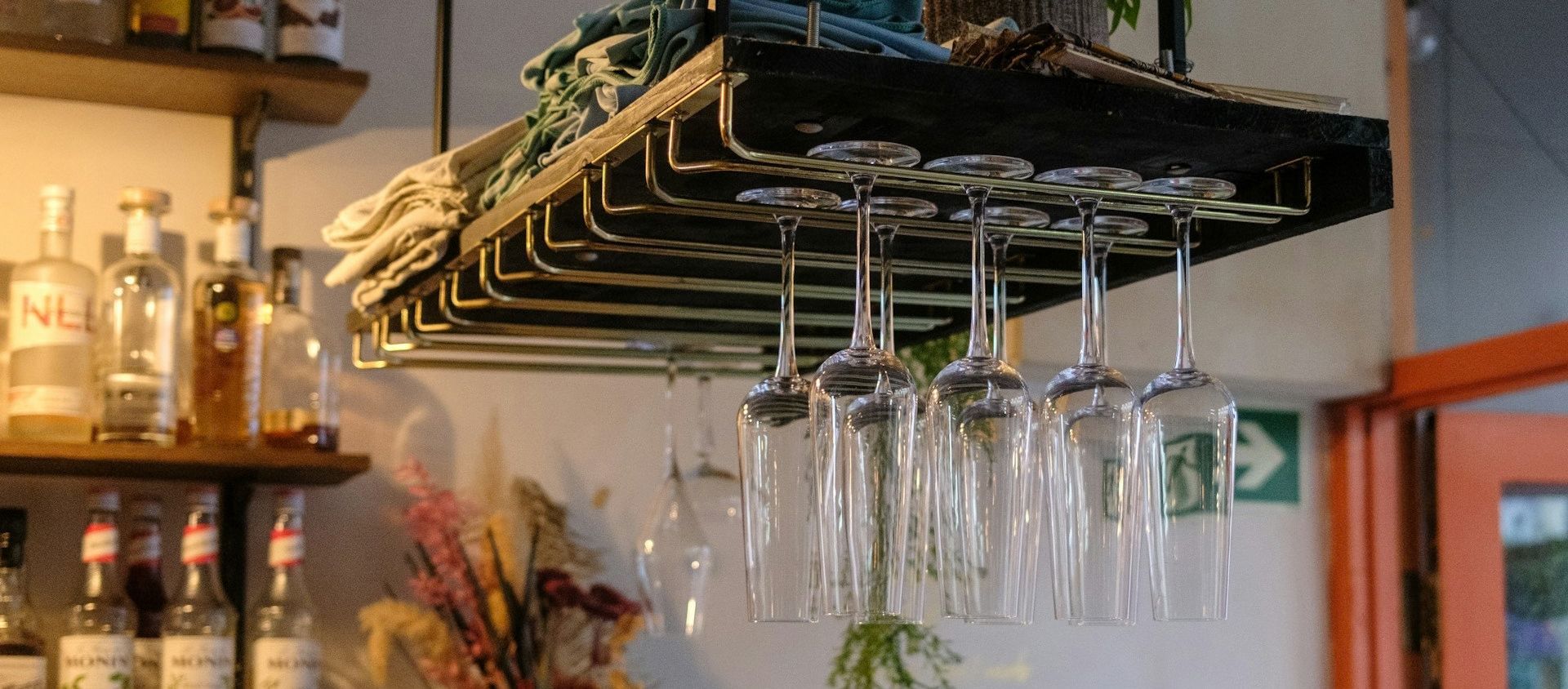Wine glasses hanging upside down on a rack above a home bar.