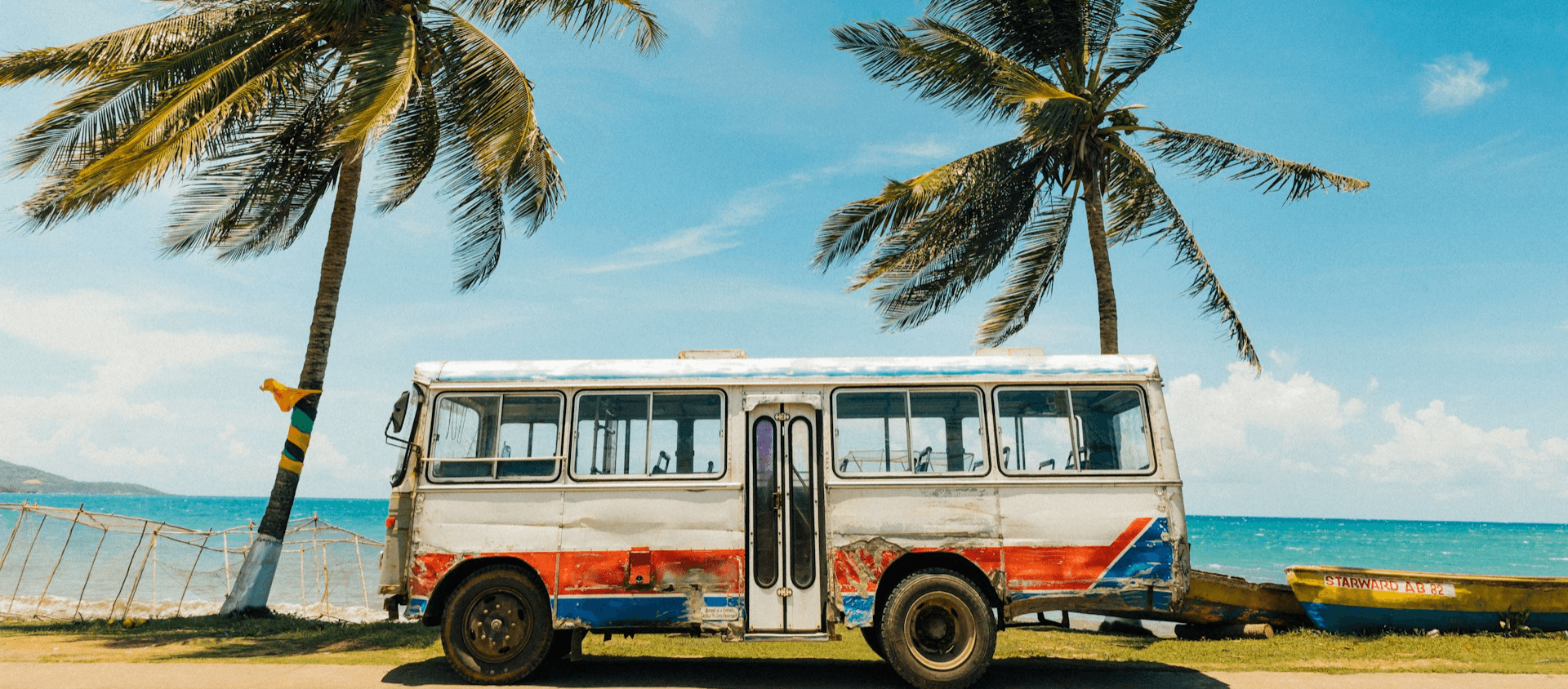 Bus parked next to a beach with palm trees
