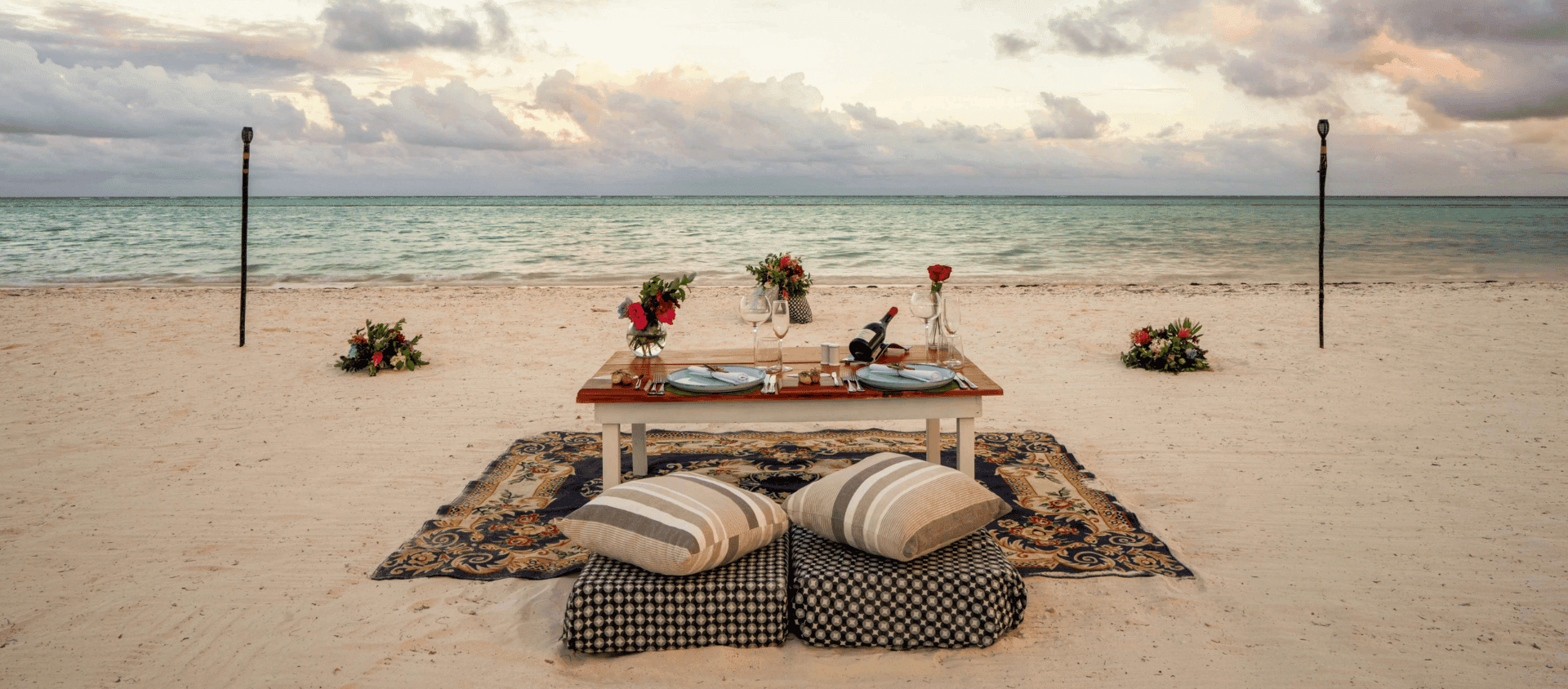 Romantic private dinner setup on the beach at sunset at Secrets Cap Cana.
