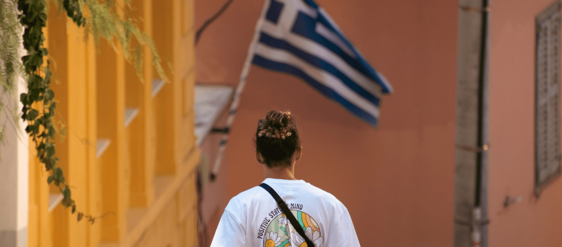 Person walking in Greece toward a Greece Flag