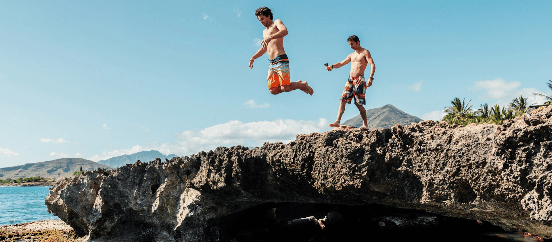Two people cliff jumping in Hawaii during the daytime