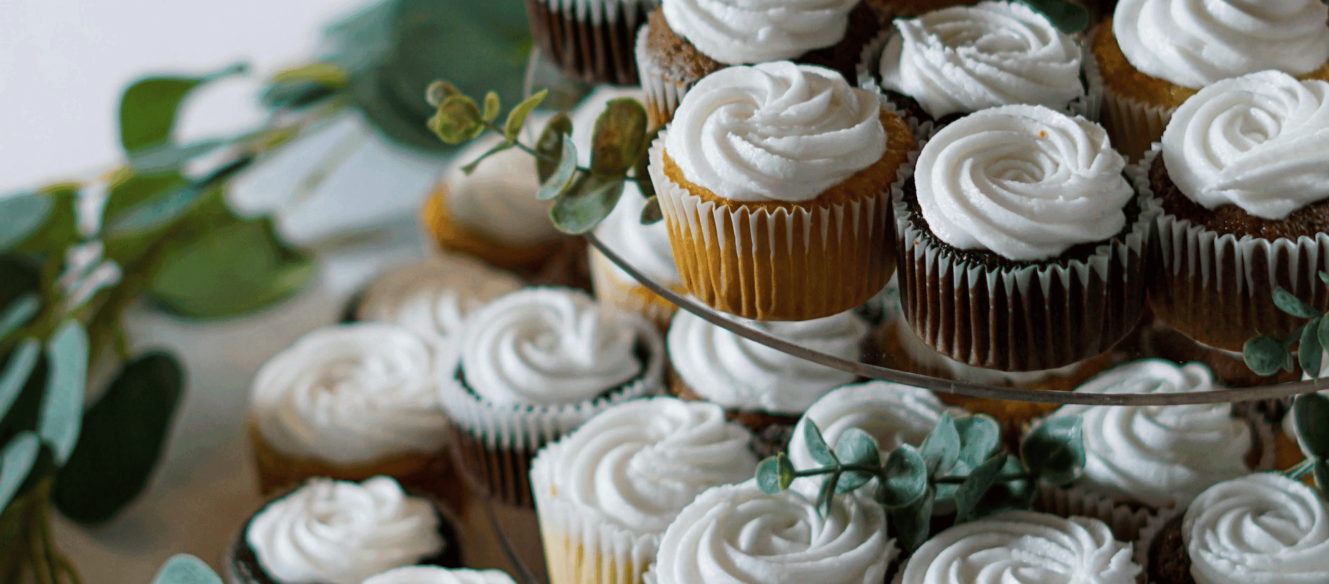 Assorted cupcakes with white frosting arranged on a tiered stand.