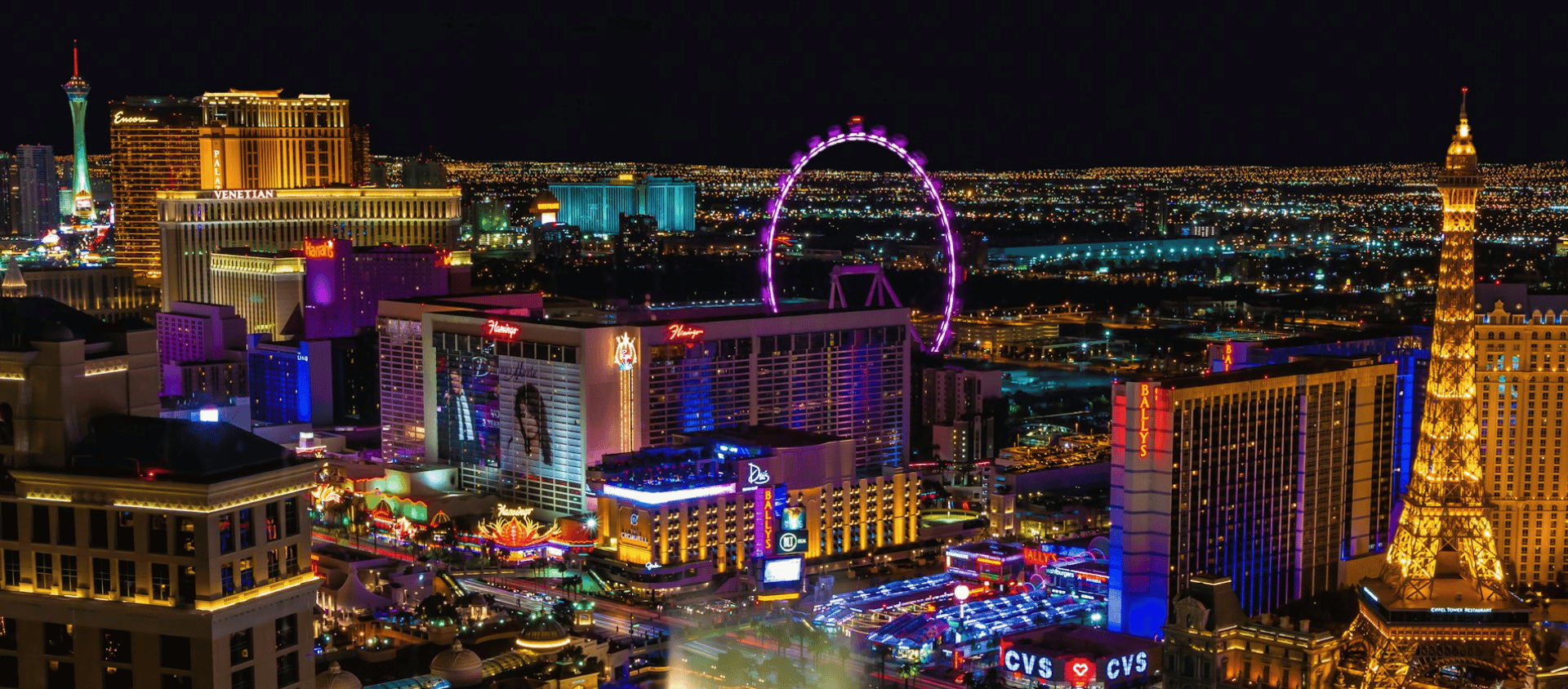 Nighttime view of the Las Vegas Strip with bright neon lights, the Bellagio fountains, and iconic hotels.
