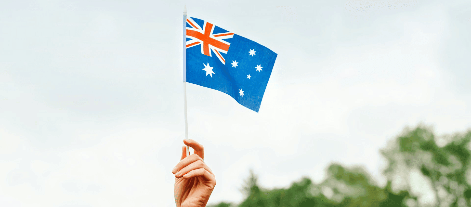 Hand waving a New Zealand flag representing travel and adventure in New Zealand