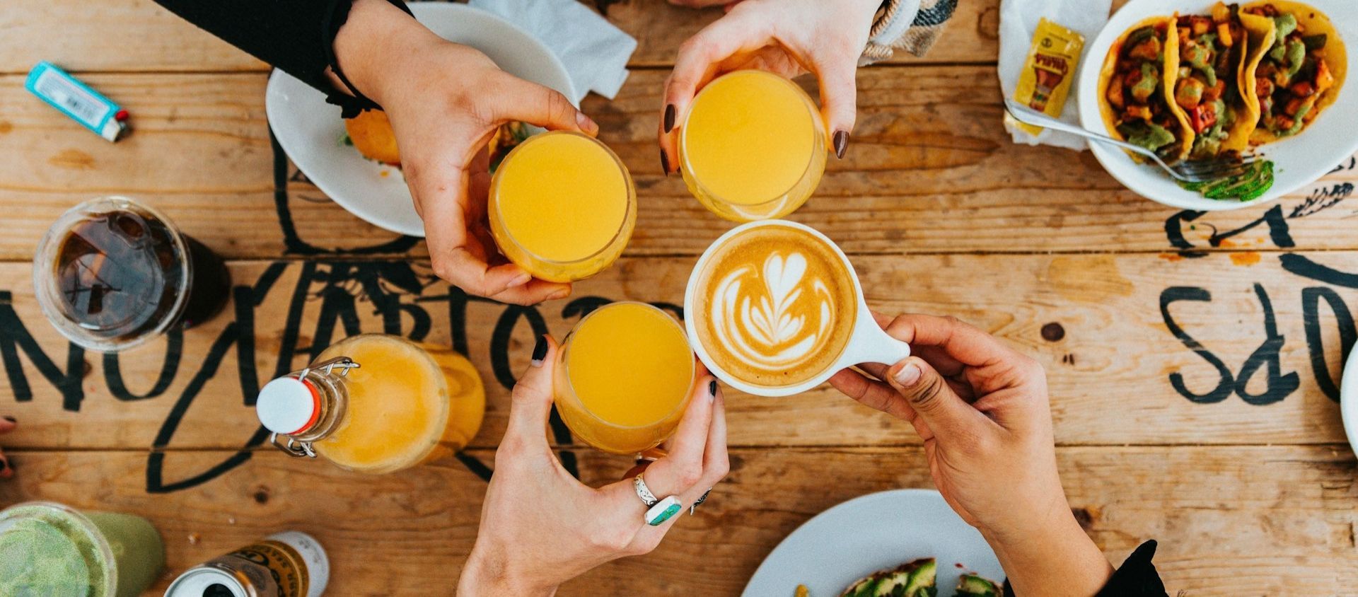 Friends gathered around a table with brunch plates and drinks.