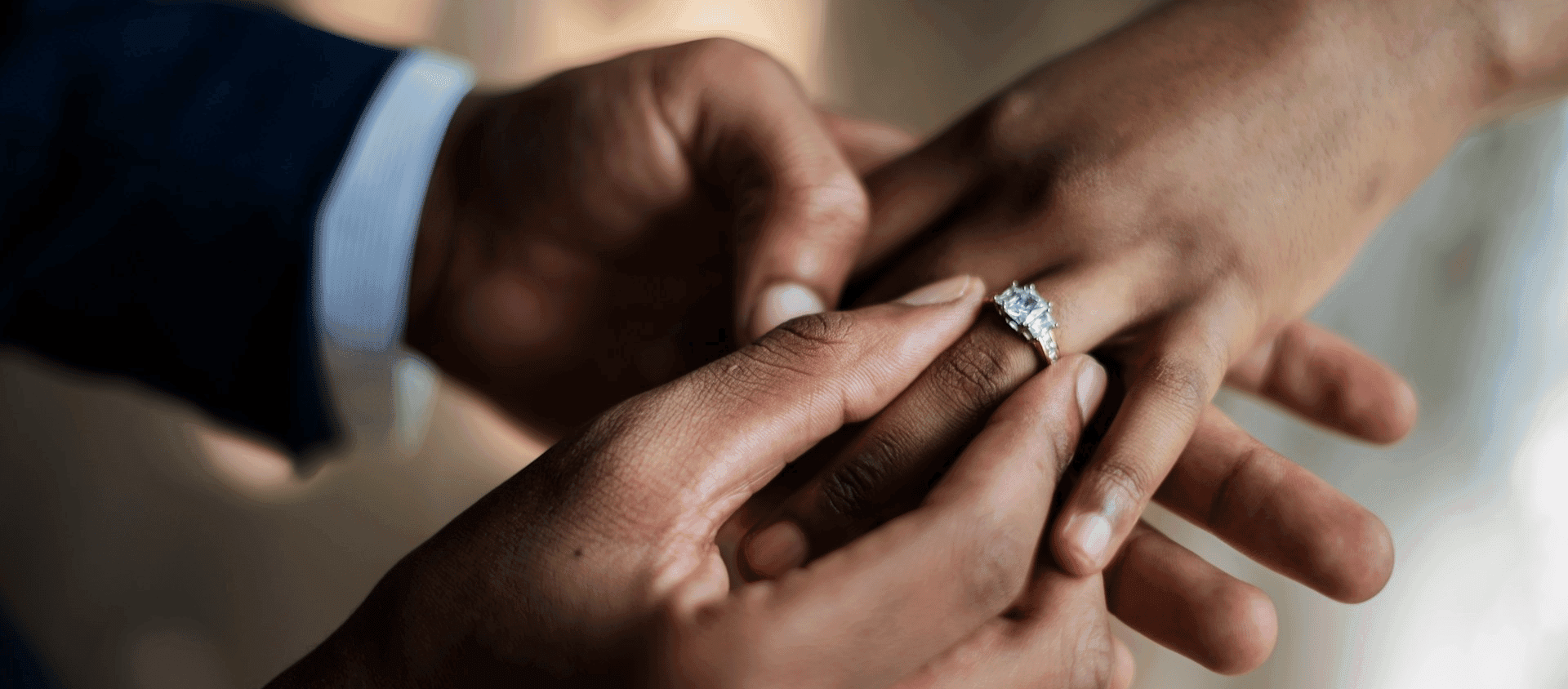 Close-up of a groom placing a wedding ring on the bride’s finger.