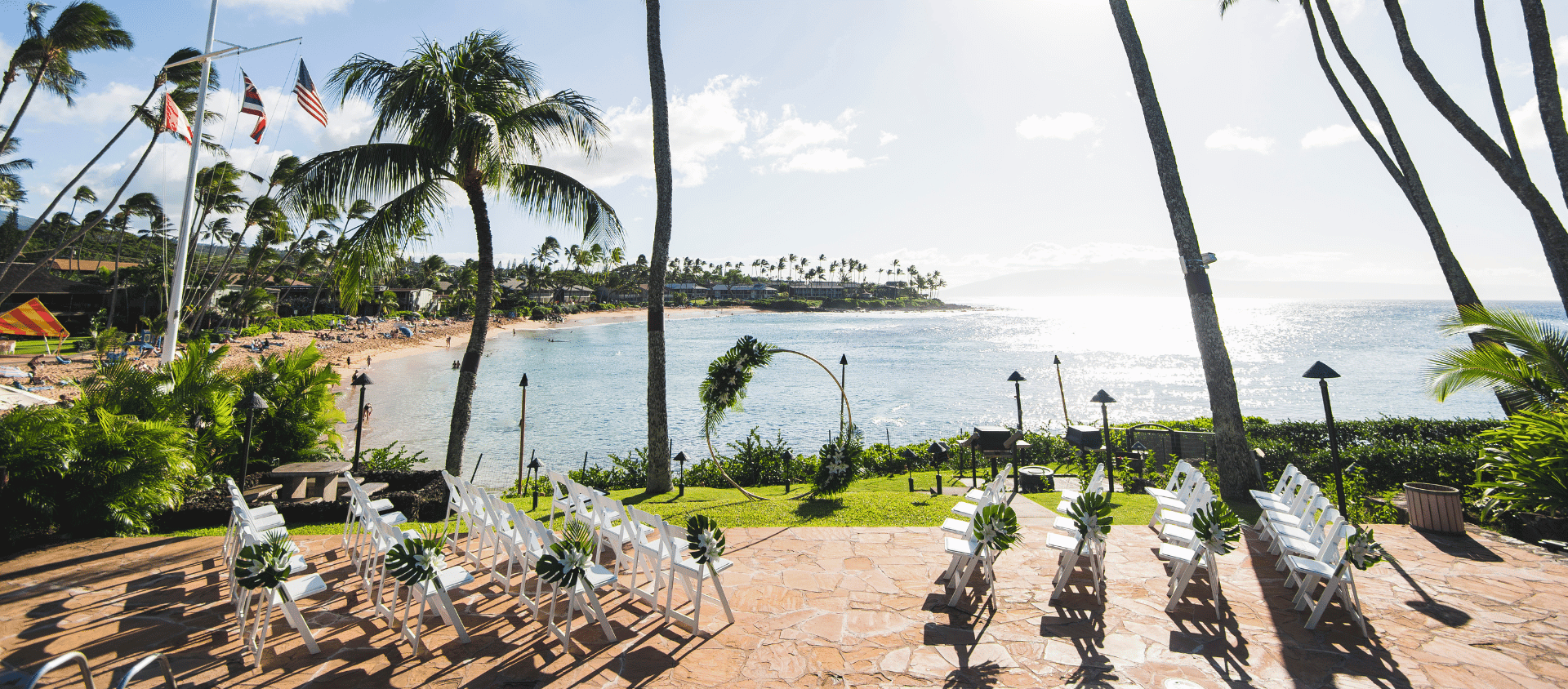 Oceanfront wedding setup at Napili Kai Beach Resort with chairs overlooking beach and palm trees.