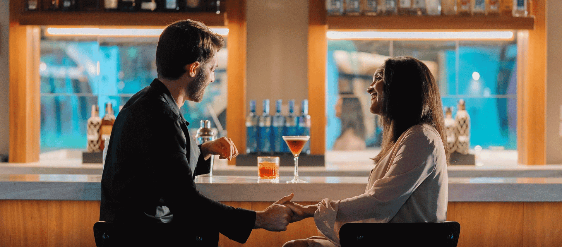 Couple sharing cocktails at a beachfront bar during a romantic escape at Secrets Playa Esmeralda.