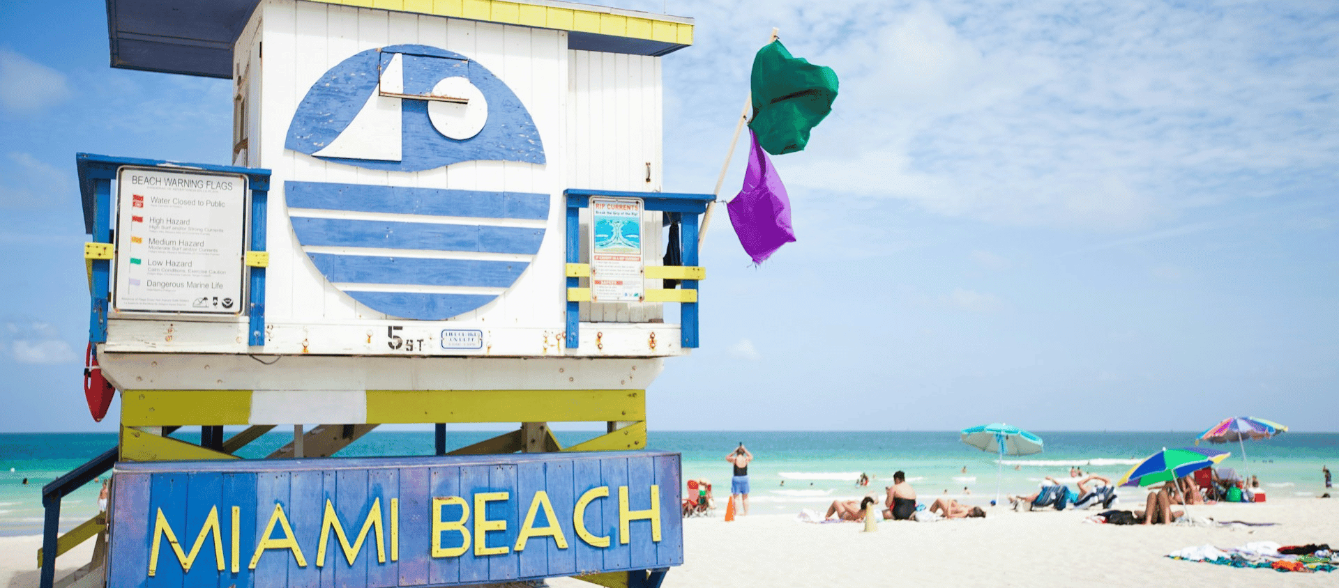 Colorful Miami Beach lifeguard tower on a wide stretch of white sand beach.