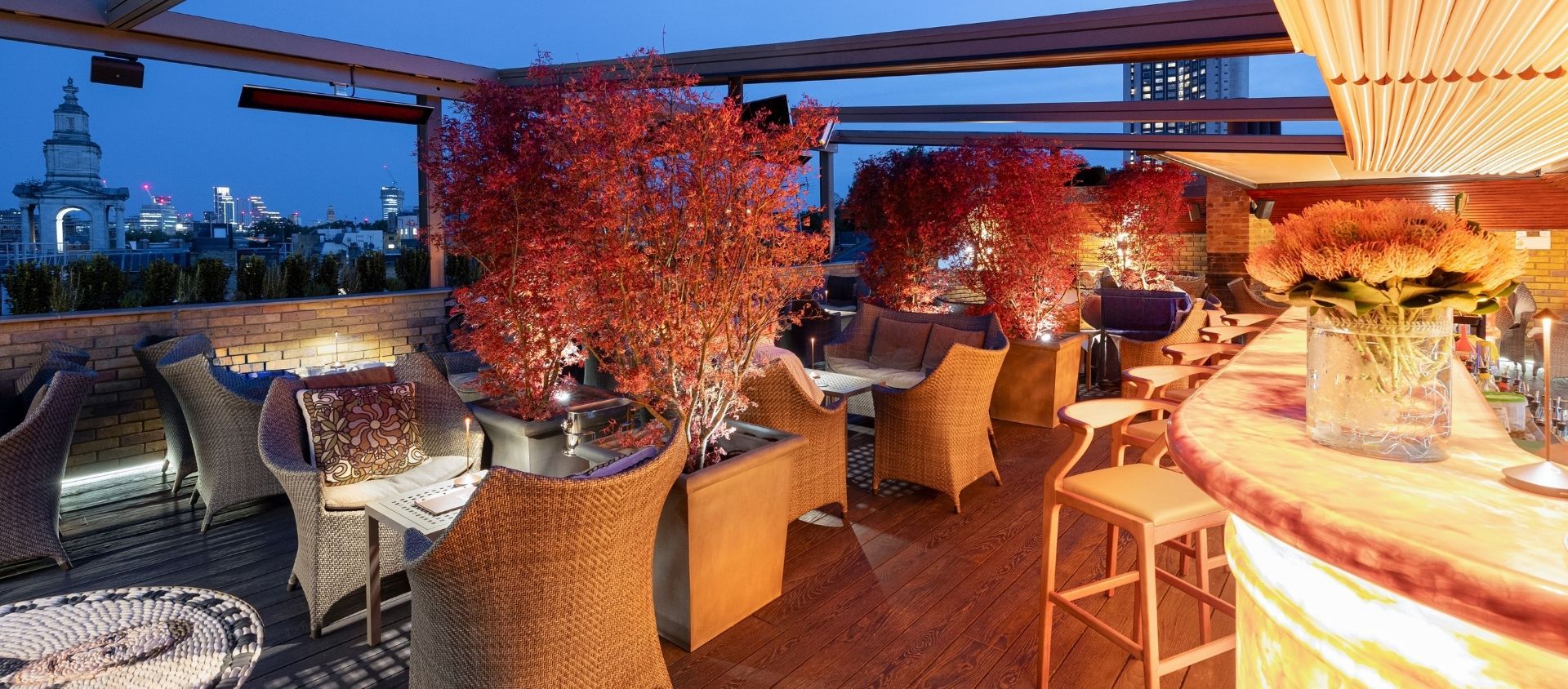 Candlelit rooftop birthday dinner tables with trees.