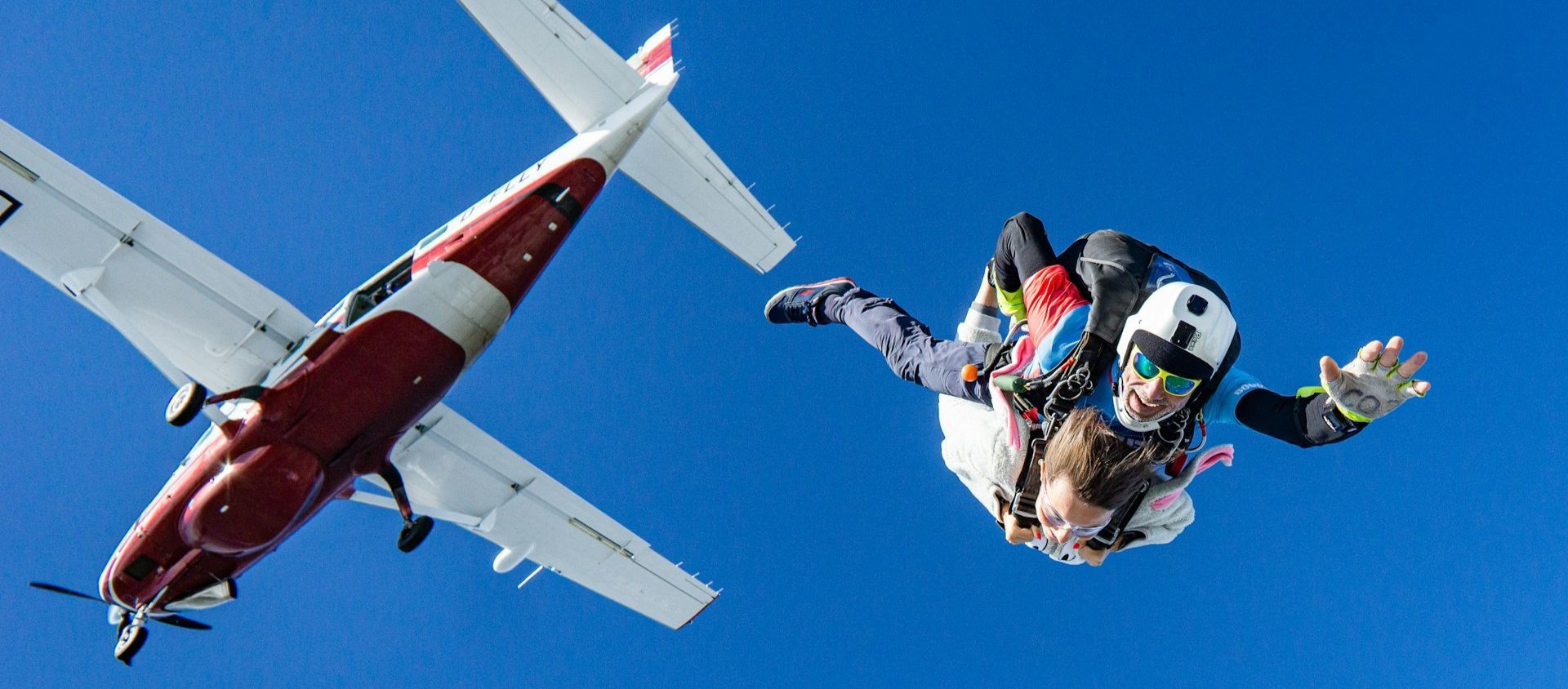 Skydivers free-falling from a plane against a blue sky.