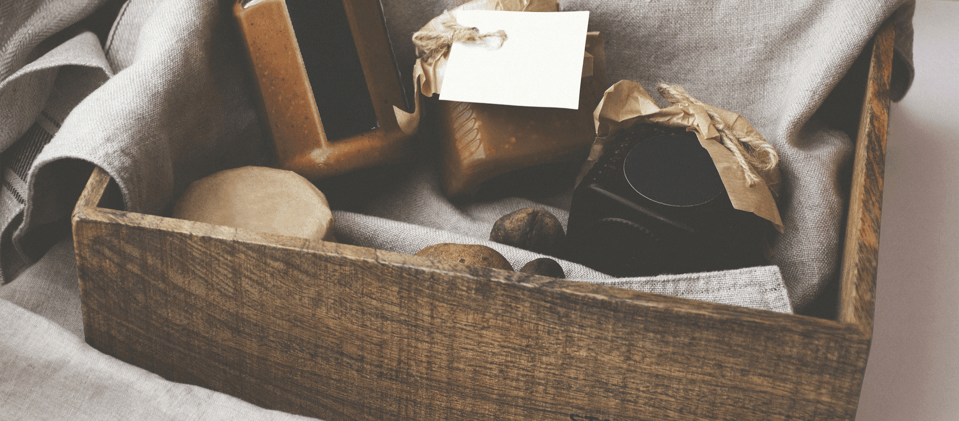 Rustic wooden gift box filled with jars and a blank card for a curated gift basket.