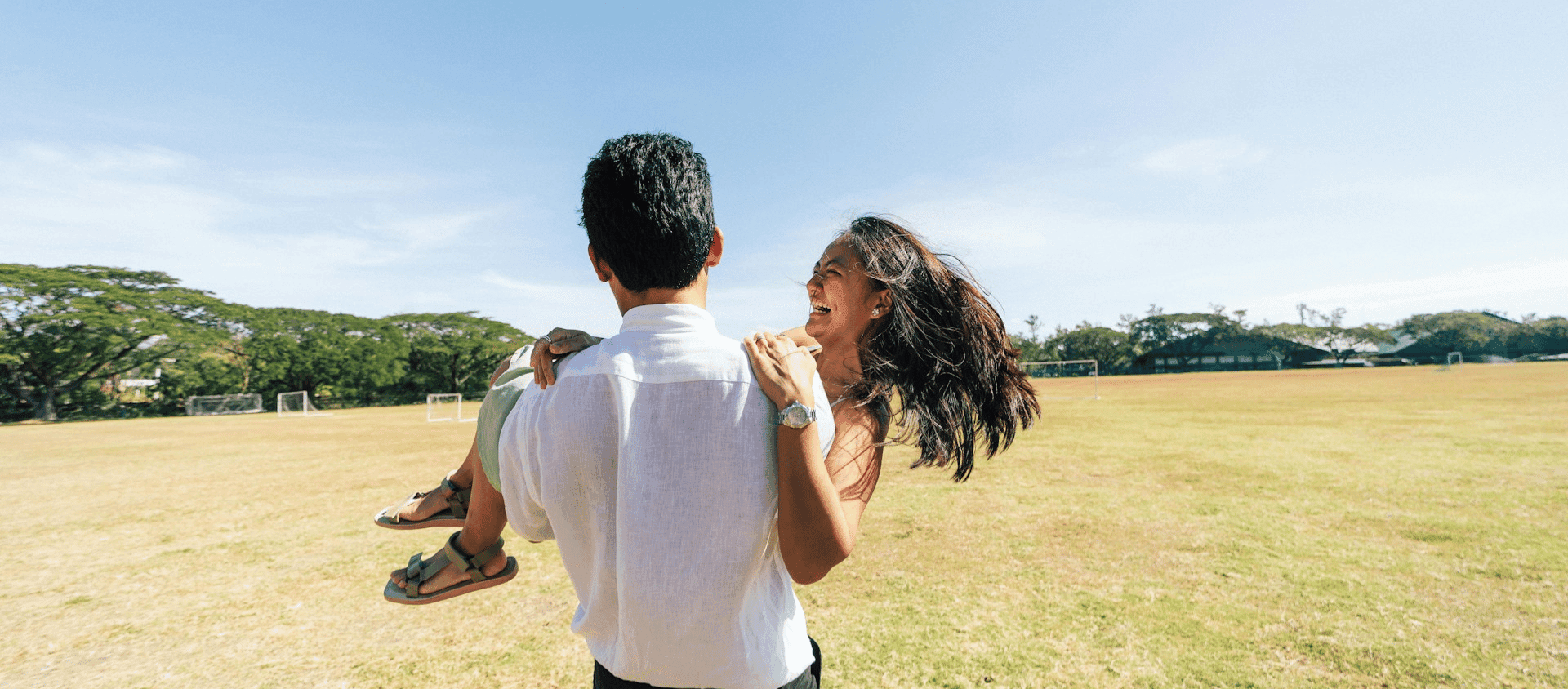 Couple celebrating outdoors with one partner lifting the other.