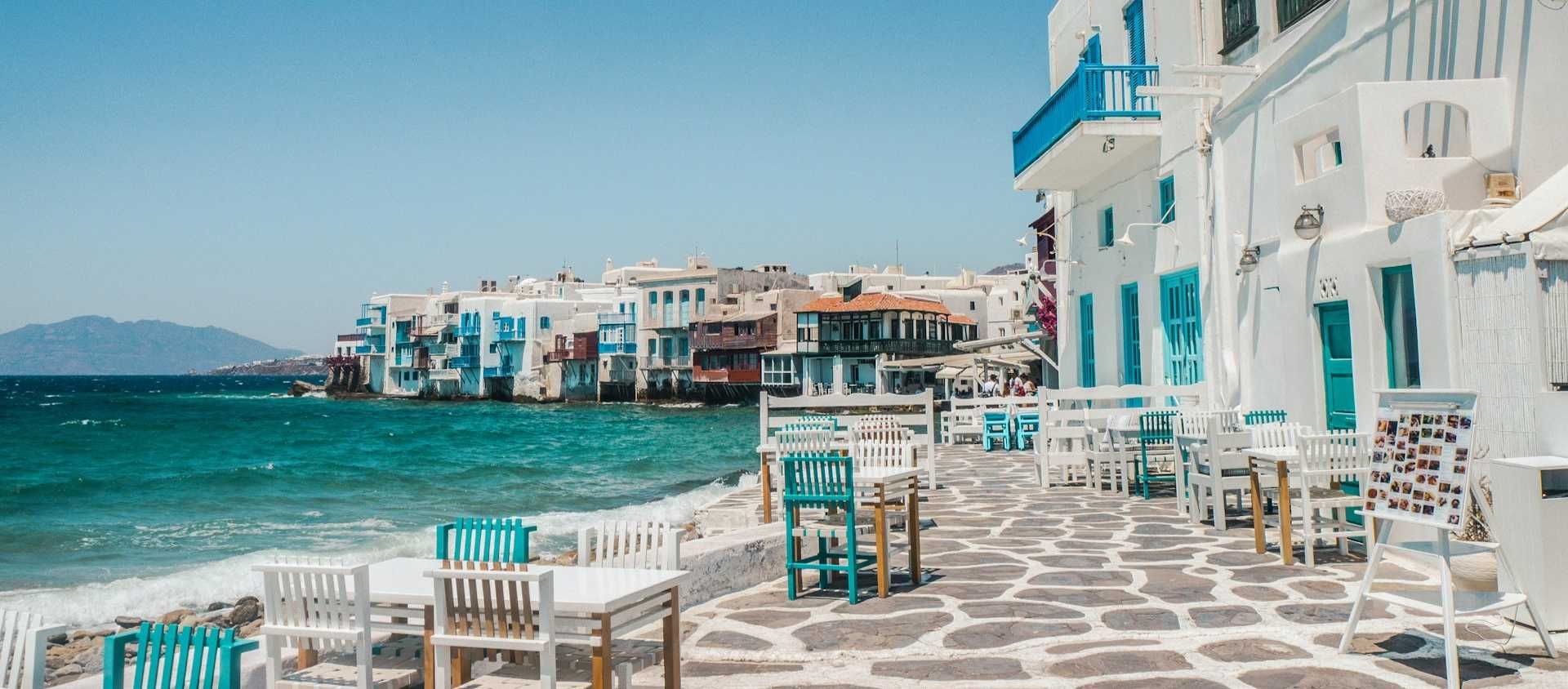 Whitewashed waterfront cafes and blue accents in Little Venice, Mykonos, Greece.