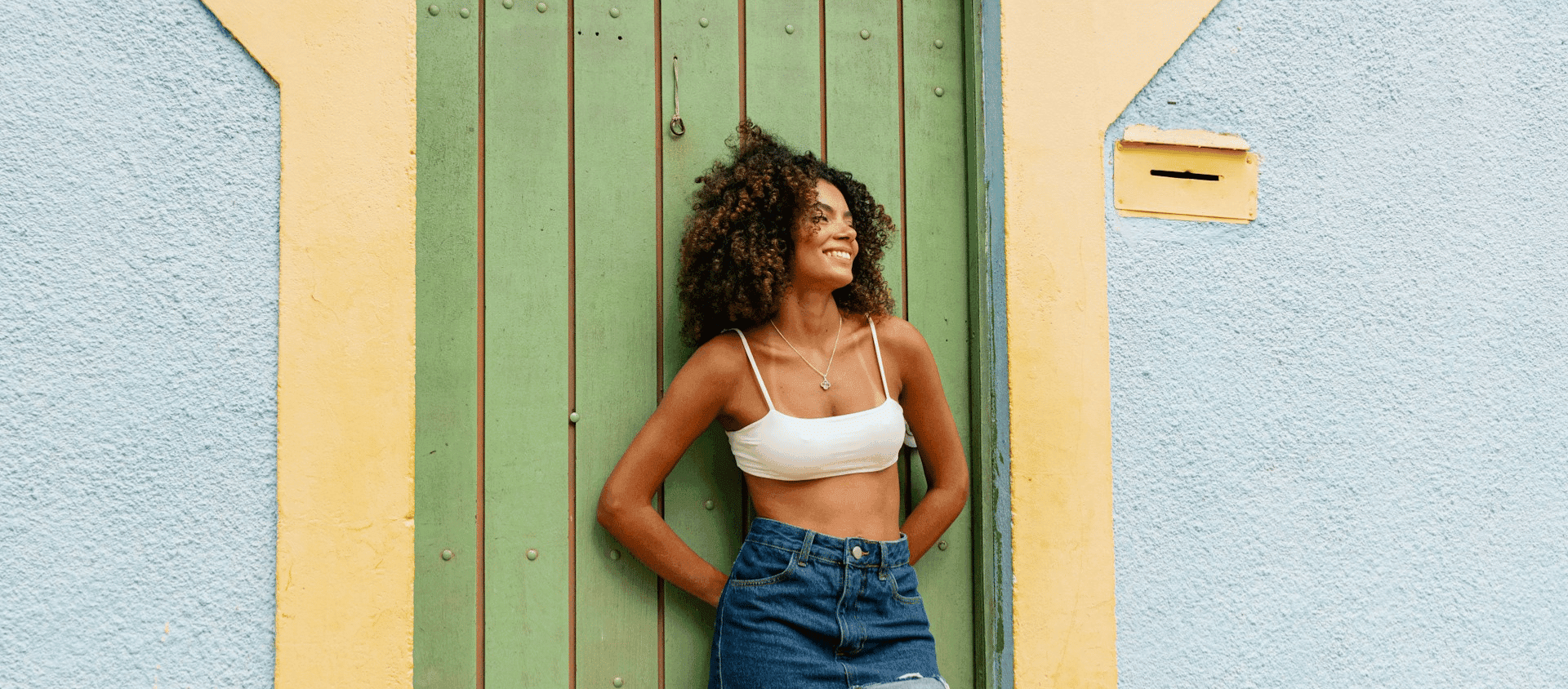Woman smiling and posing in front of colorful painted doors in Puerto Rico.