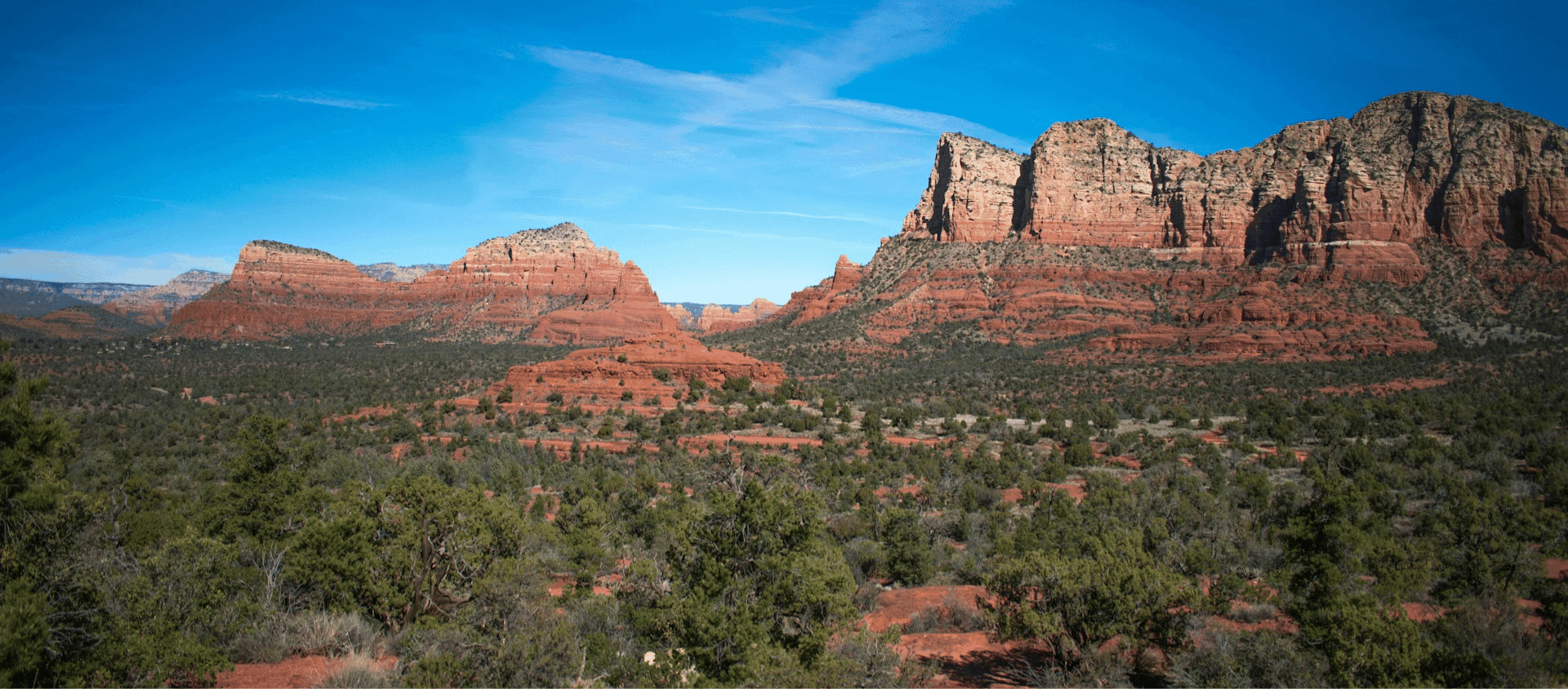 Red rock formations and desert landscape under a bright blue sky in Sedona, Arizona.