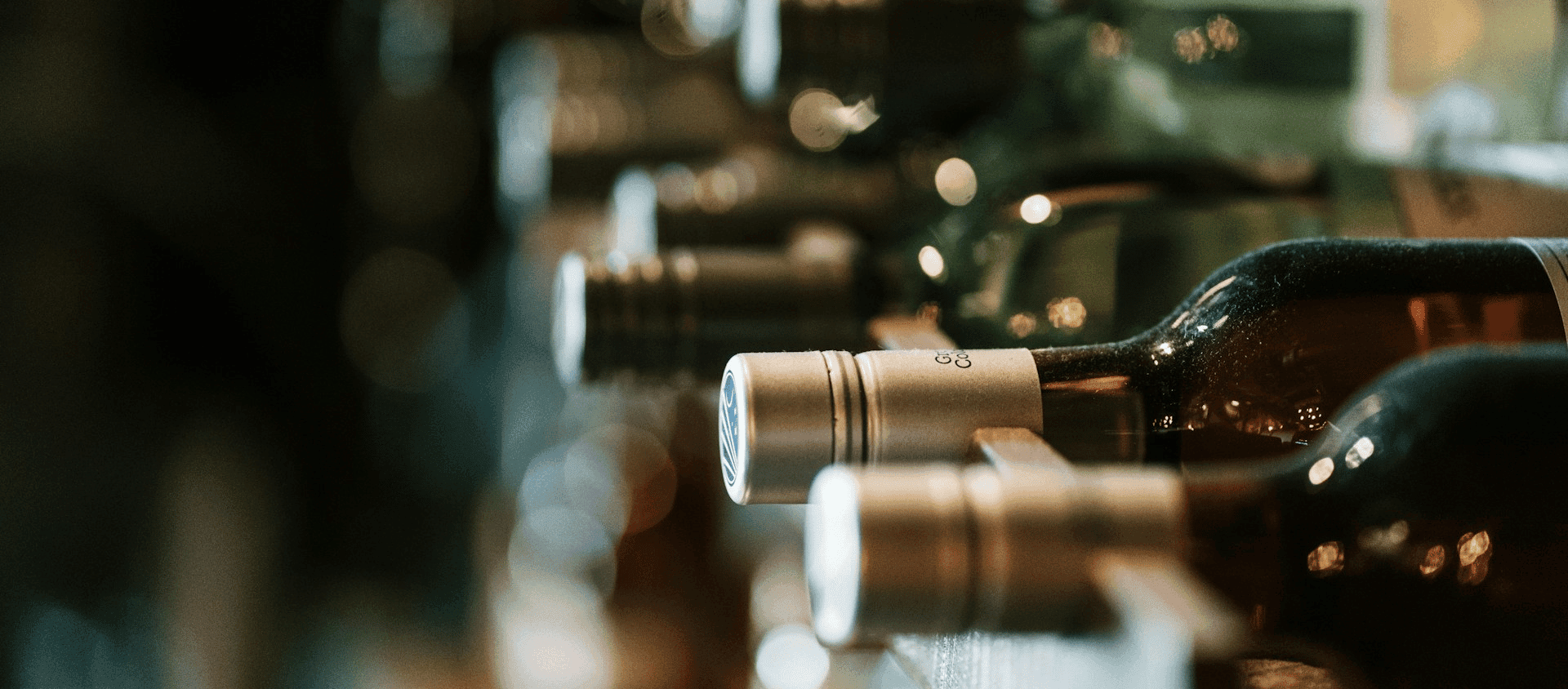 Row of wine bottles resting on their sides in a cellar.