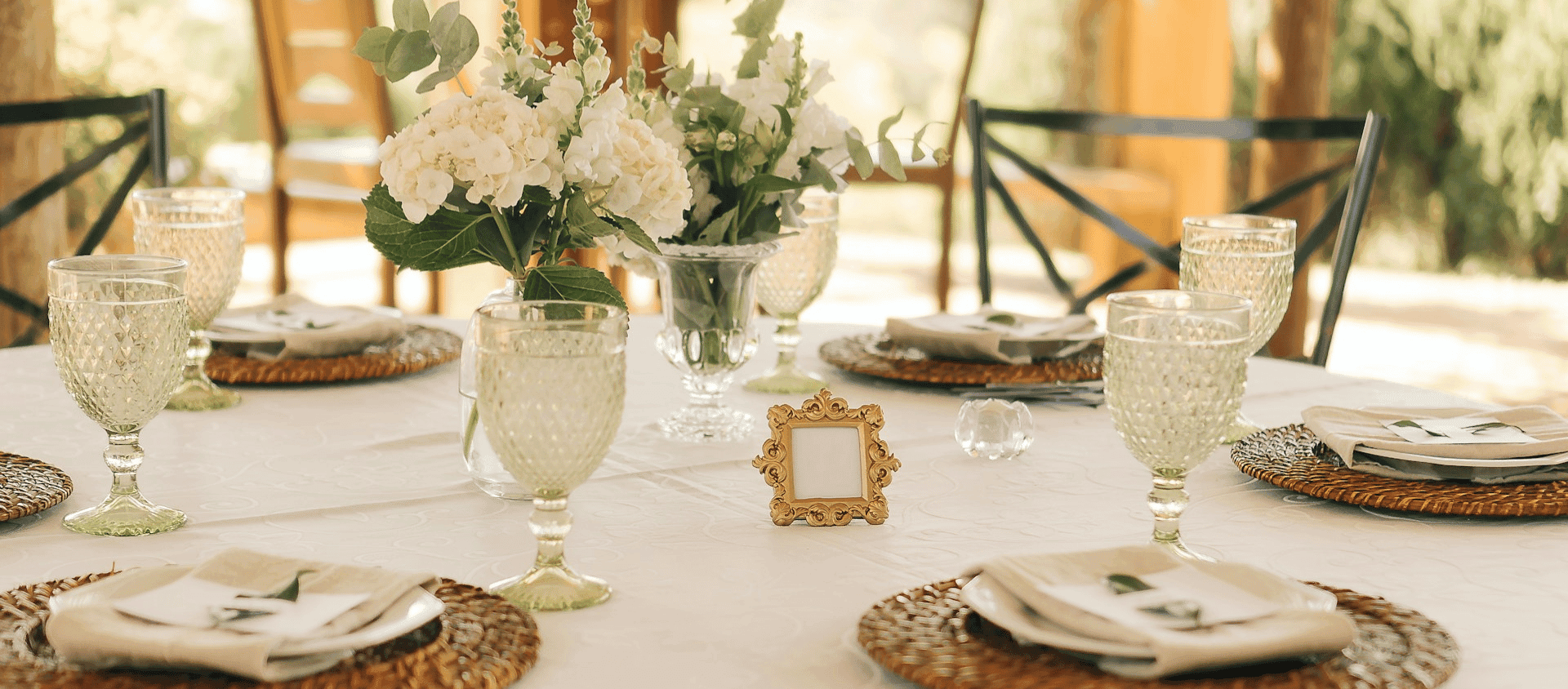 Elegant table setting with glassware, white linens, and a floral centerpiece.
