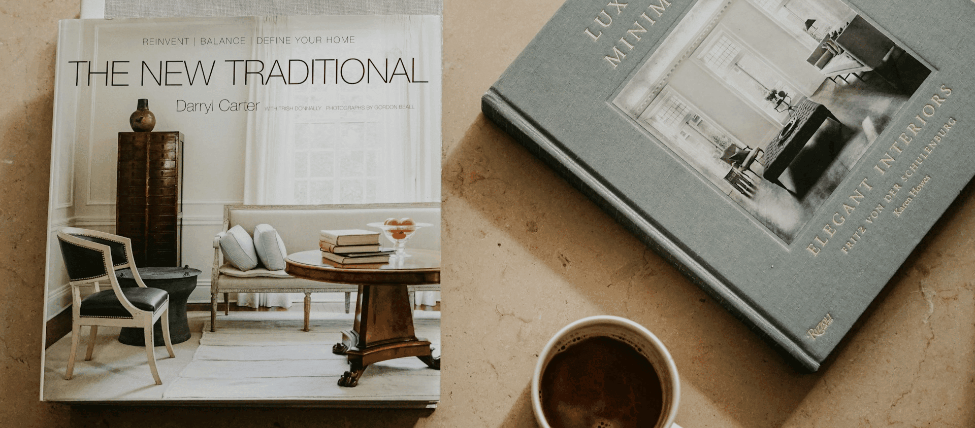Two interior design coffee table books beside a mug of coffee.