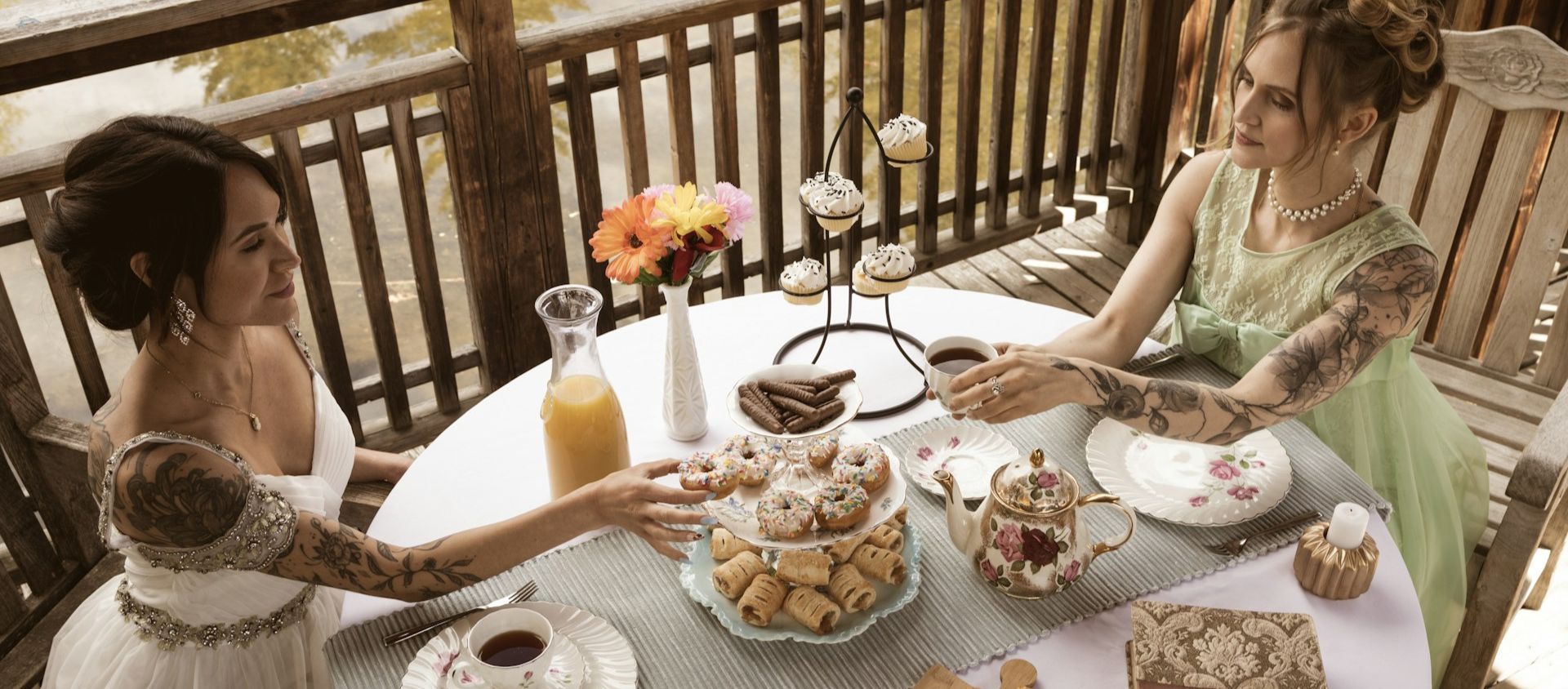 Two friends in vintage dresses at an outdoor high tea.