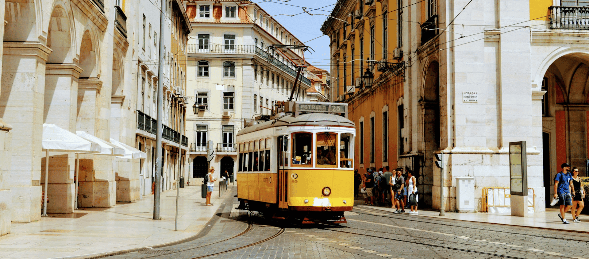 Yellow tram in Lisbon, Portugal passing through a sunlit street lined with old buildings
