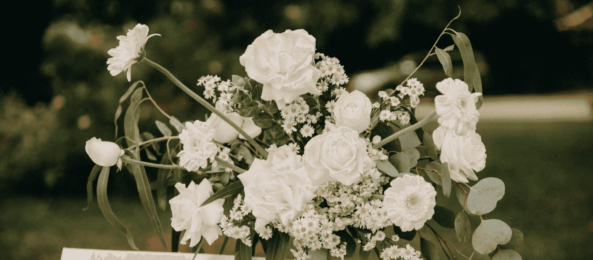Bouquet of white roses and daisies with greenery.