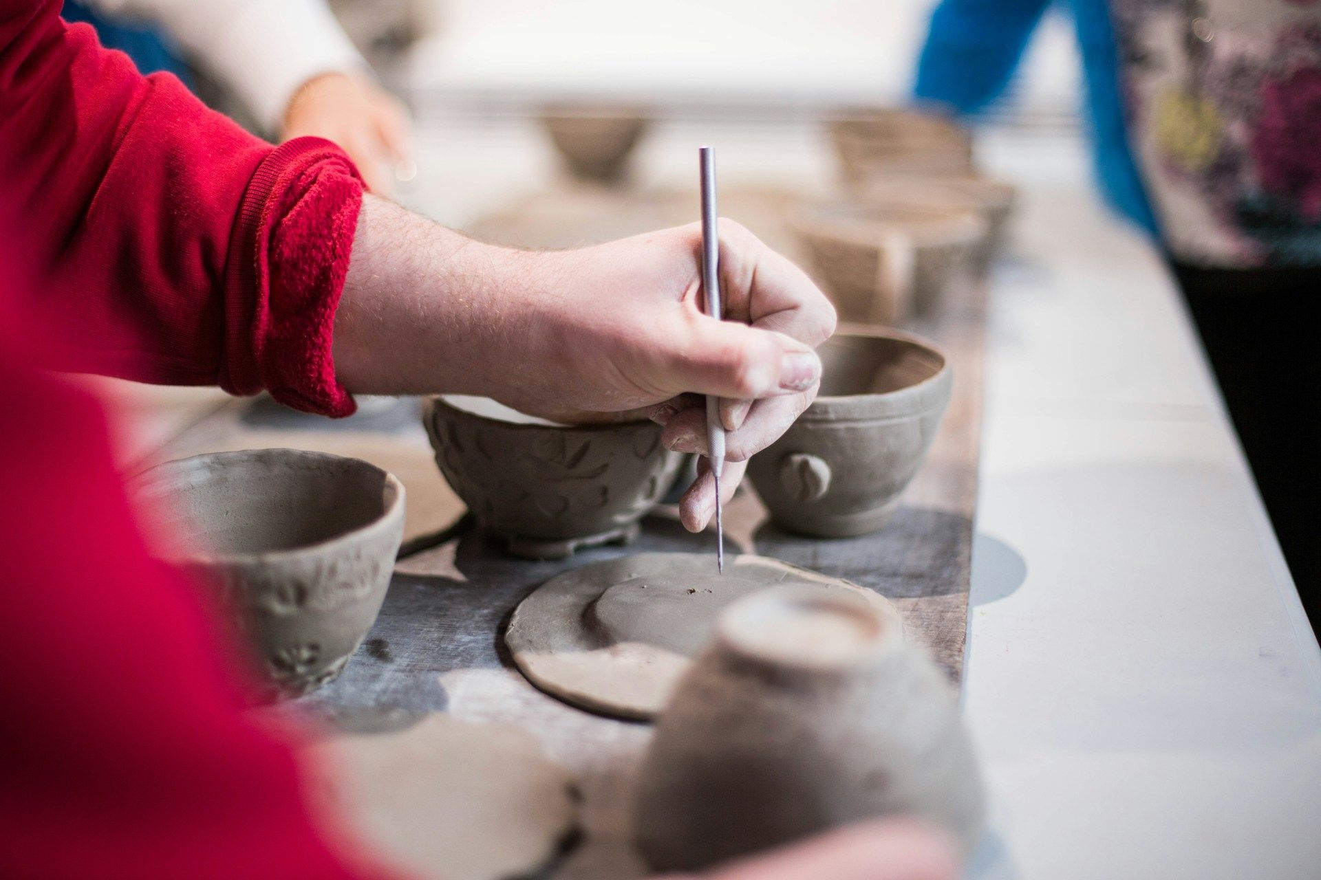 Close up of a person carving details into a clay bowl in a pottery workshop.