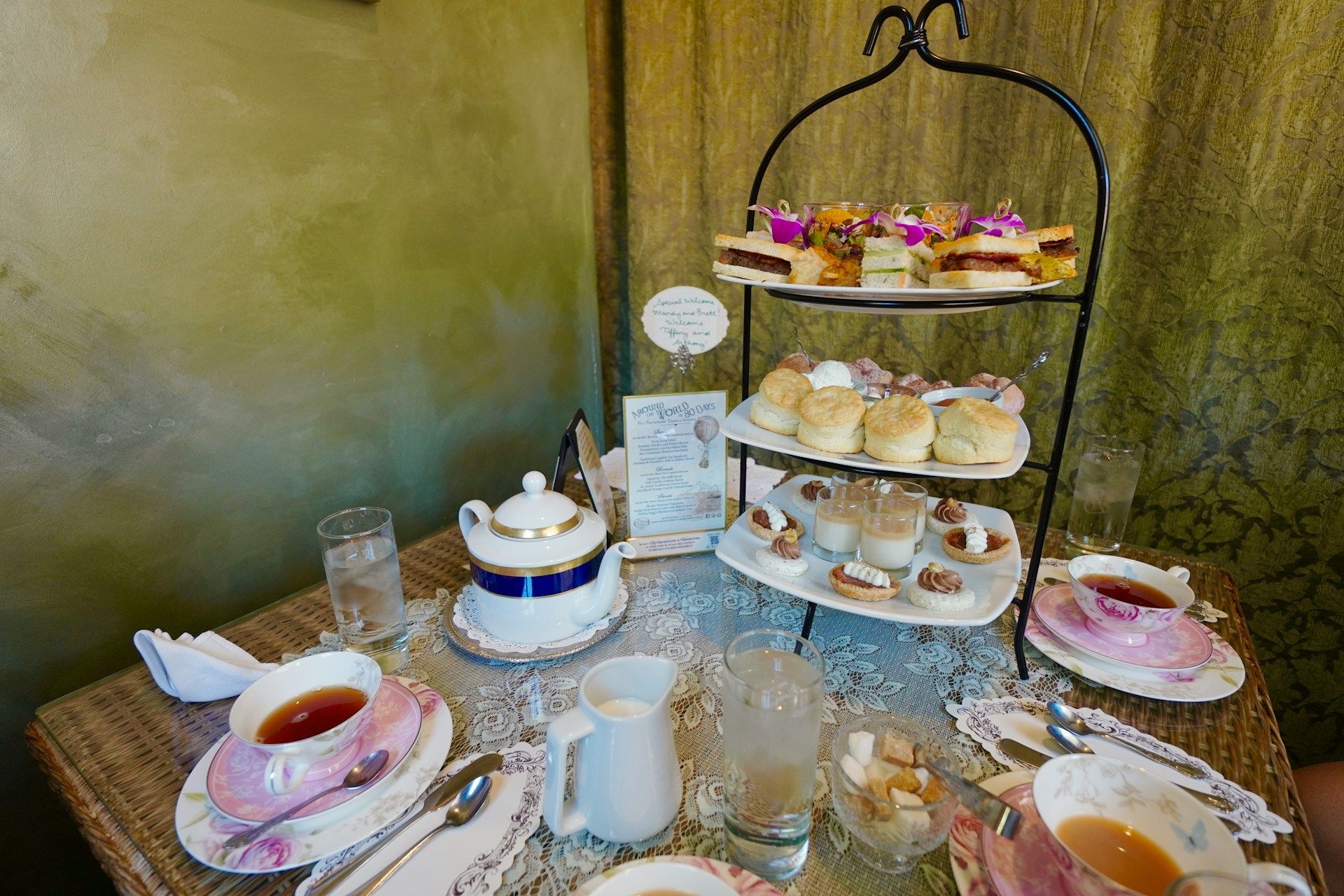 Afternoon tea spread with tiered tray, teapot, and pastries.