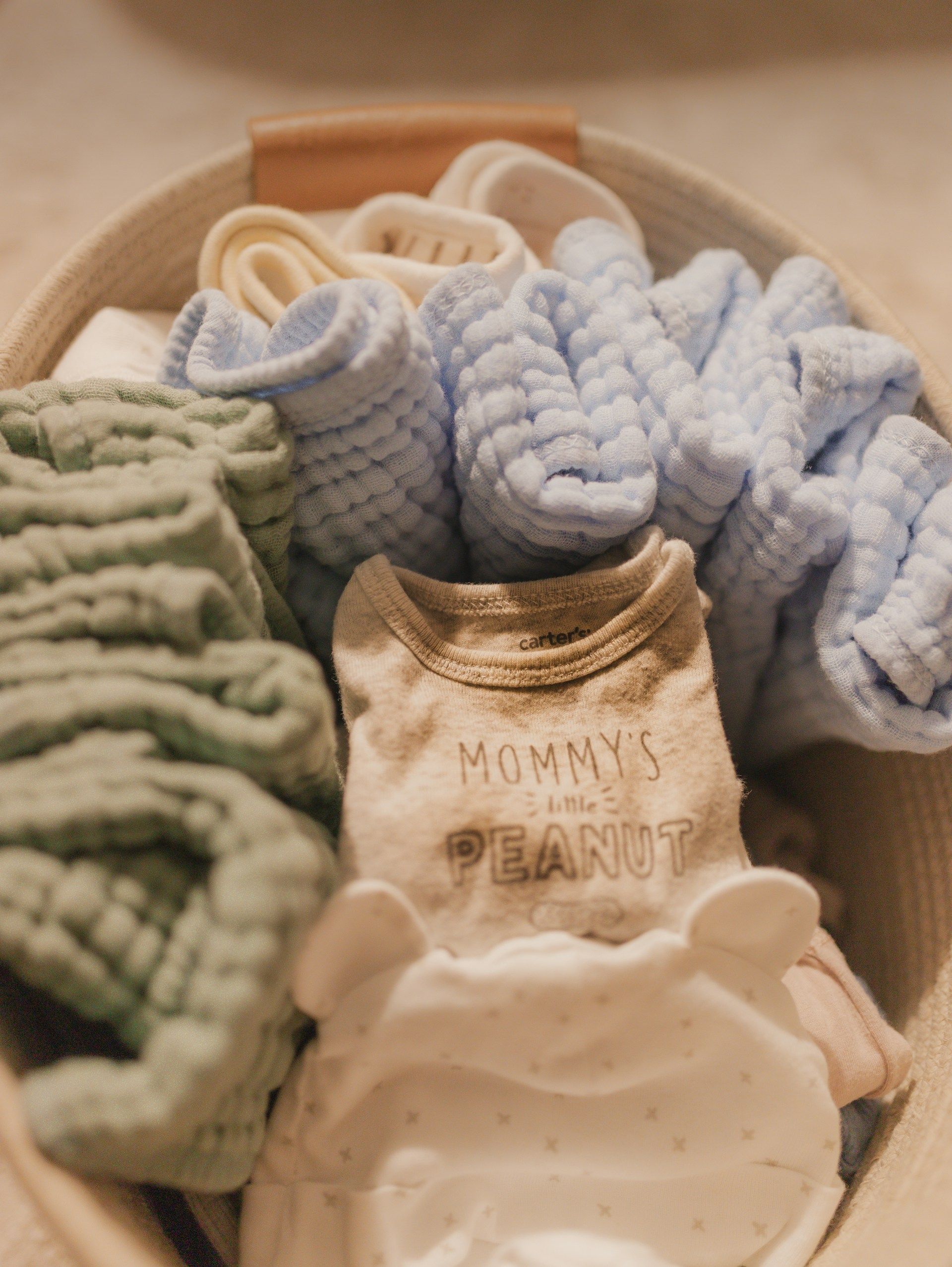Basket filled with folded baby clothes and blankets.