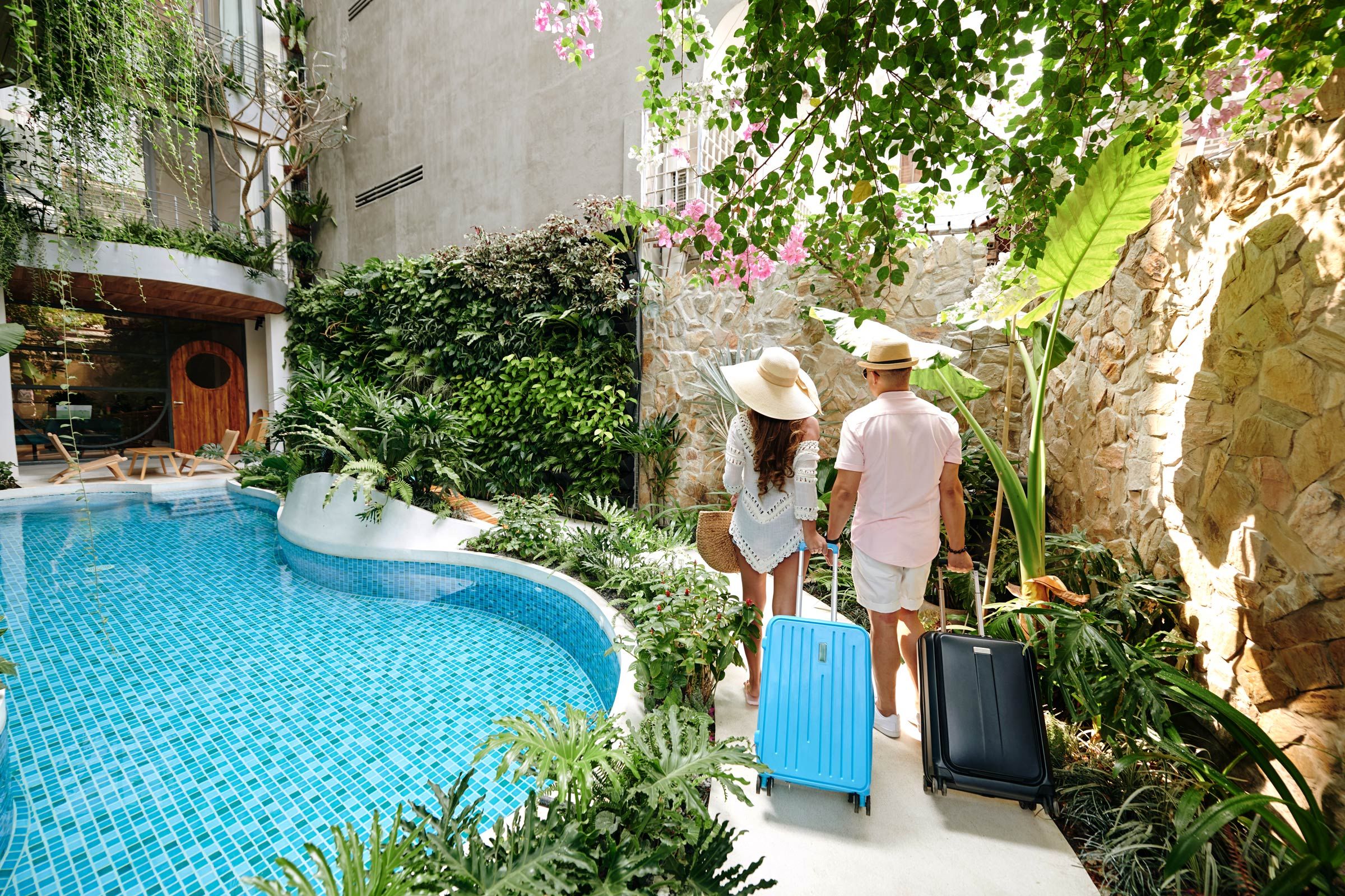 Couple with suitcases arriving at a tropical luxury hotel.