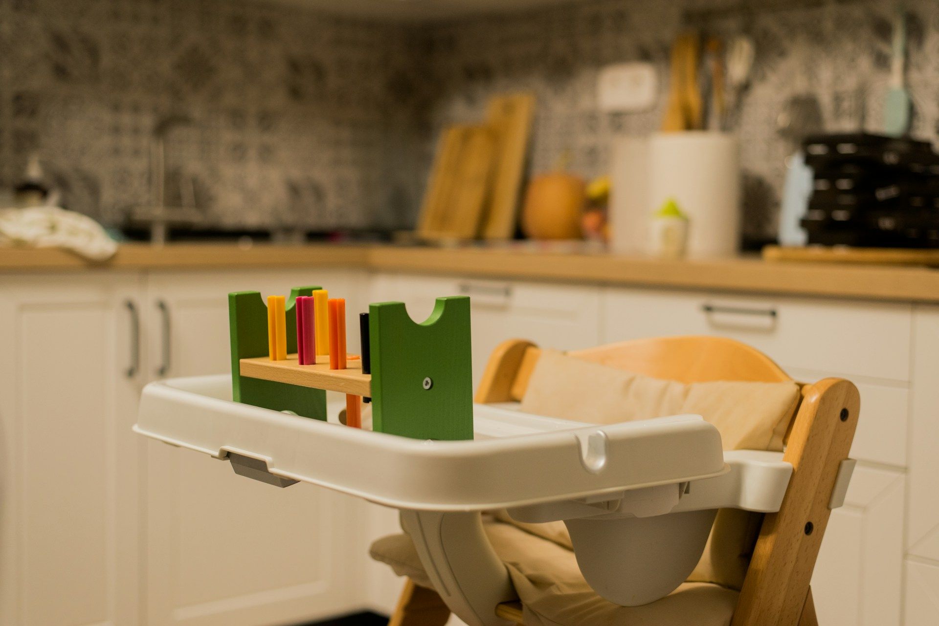 Wooden baby high chair with tray toy in a kitchen.