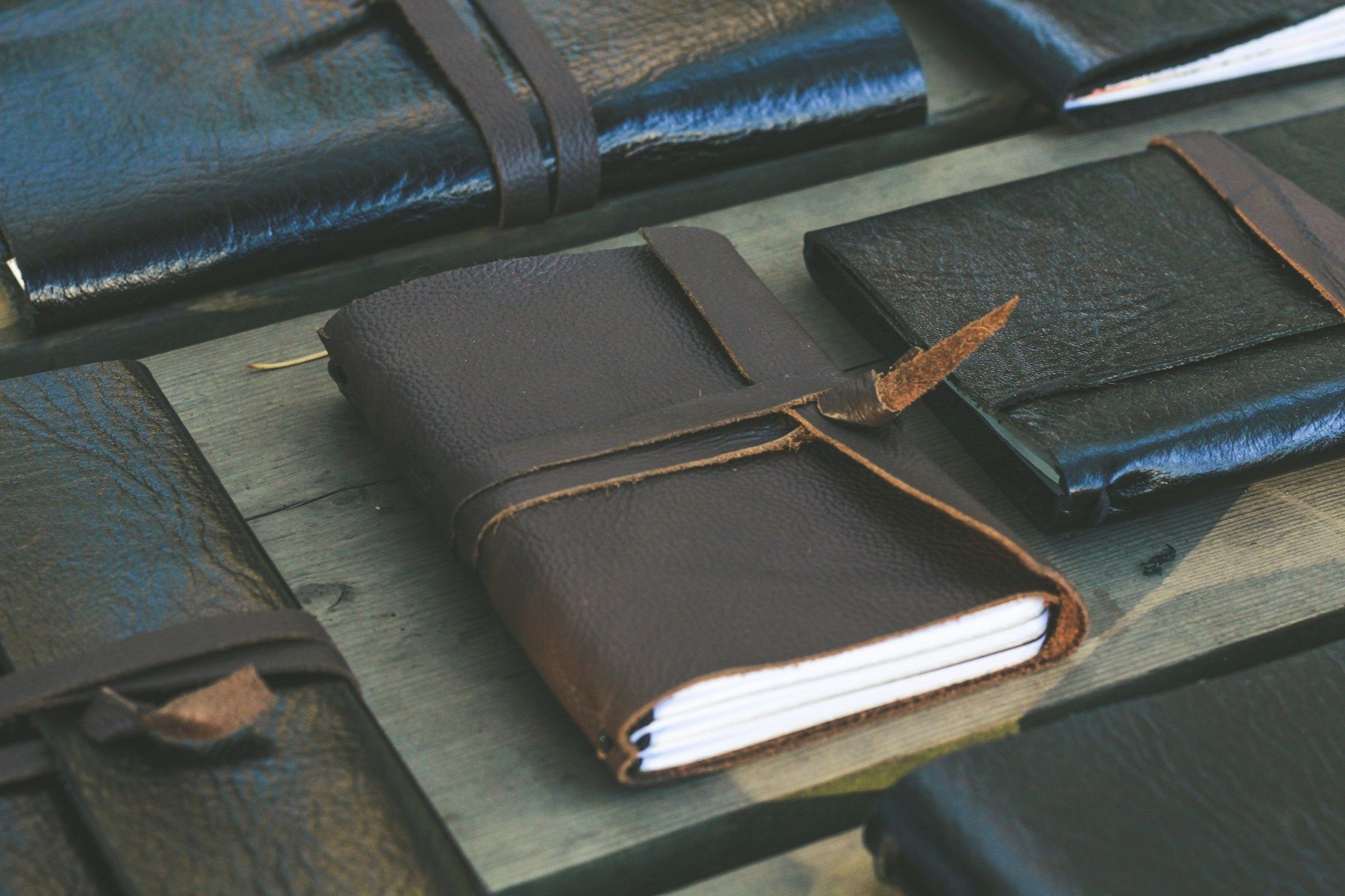 Handmade leather travel journals tied with cord on a wooden surface.