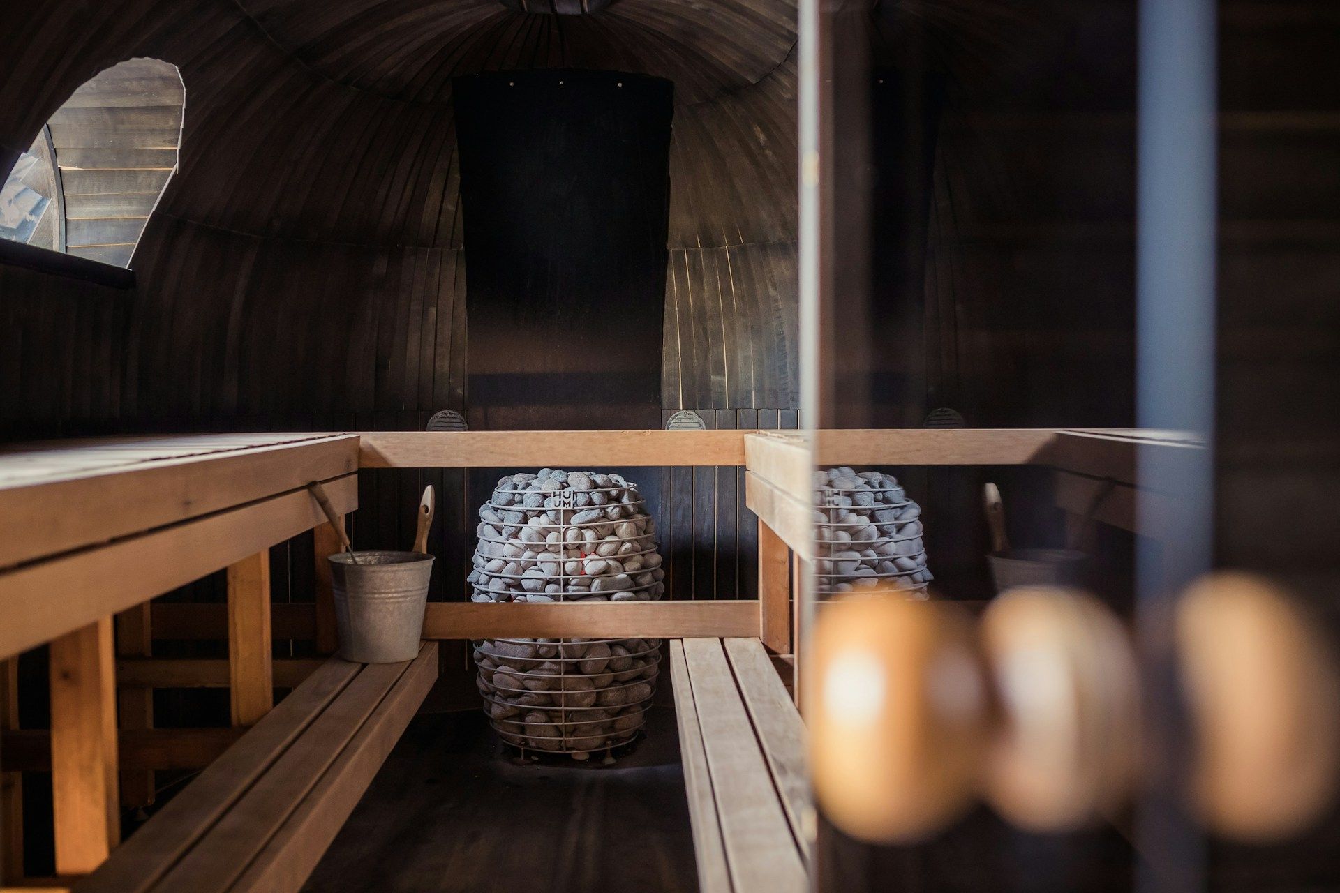Interior of a wooden sauna with a heated rock stove and bench seating.