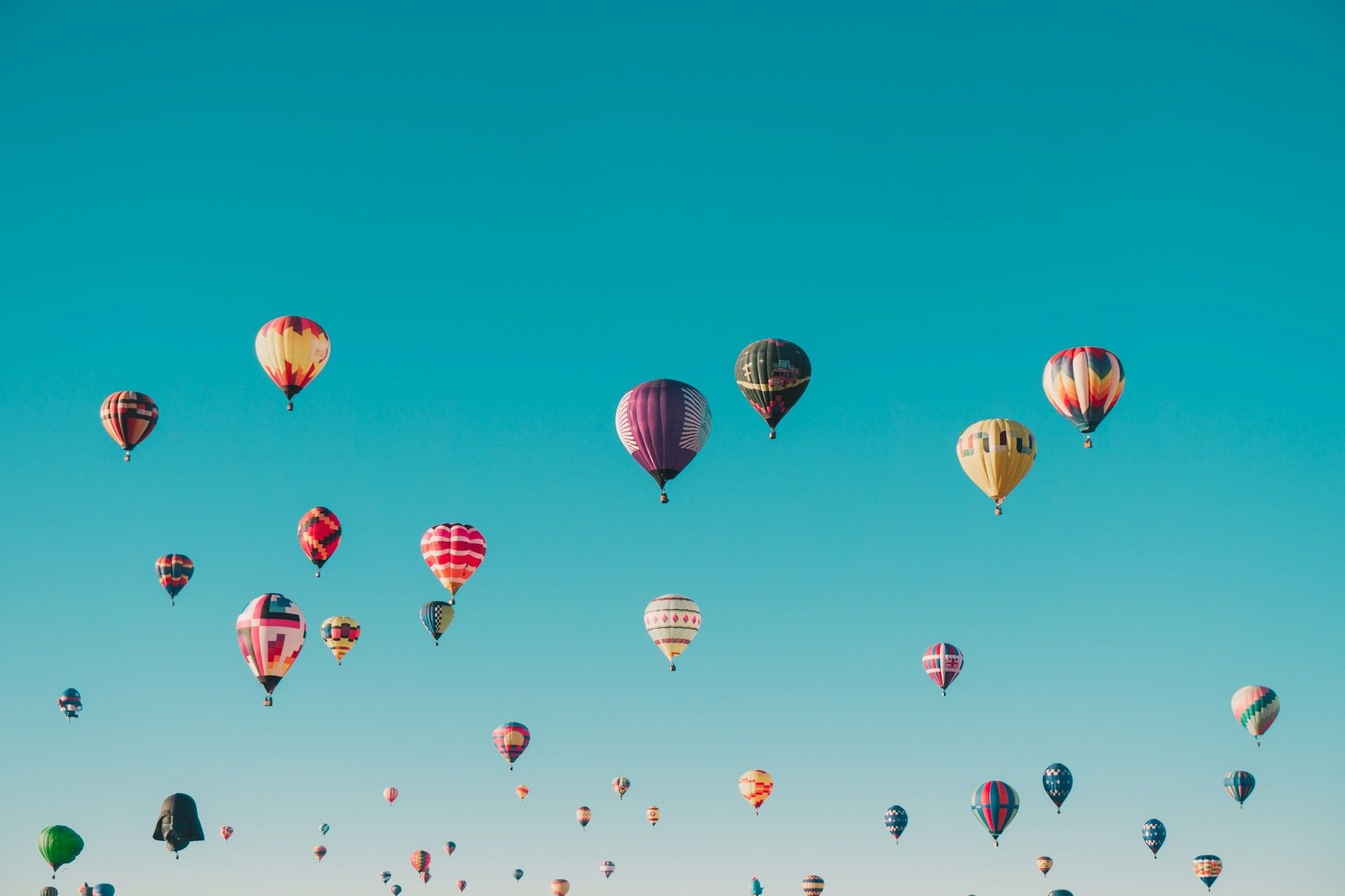 Colorful hot air balloons floating in a clear blue sky.