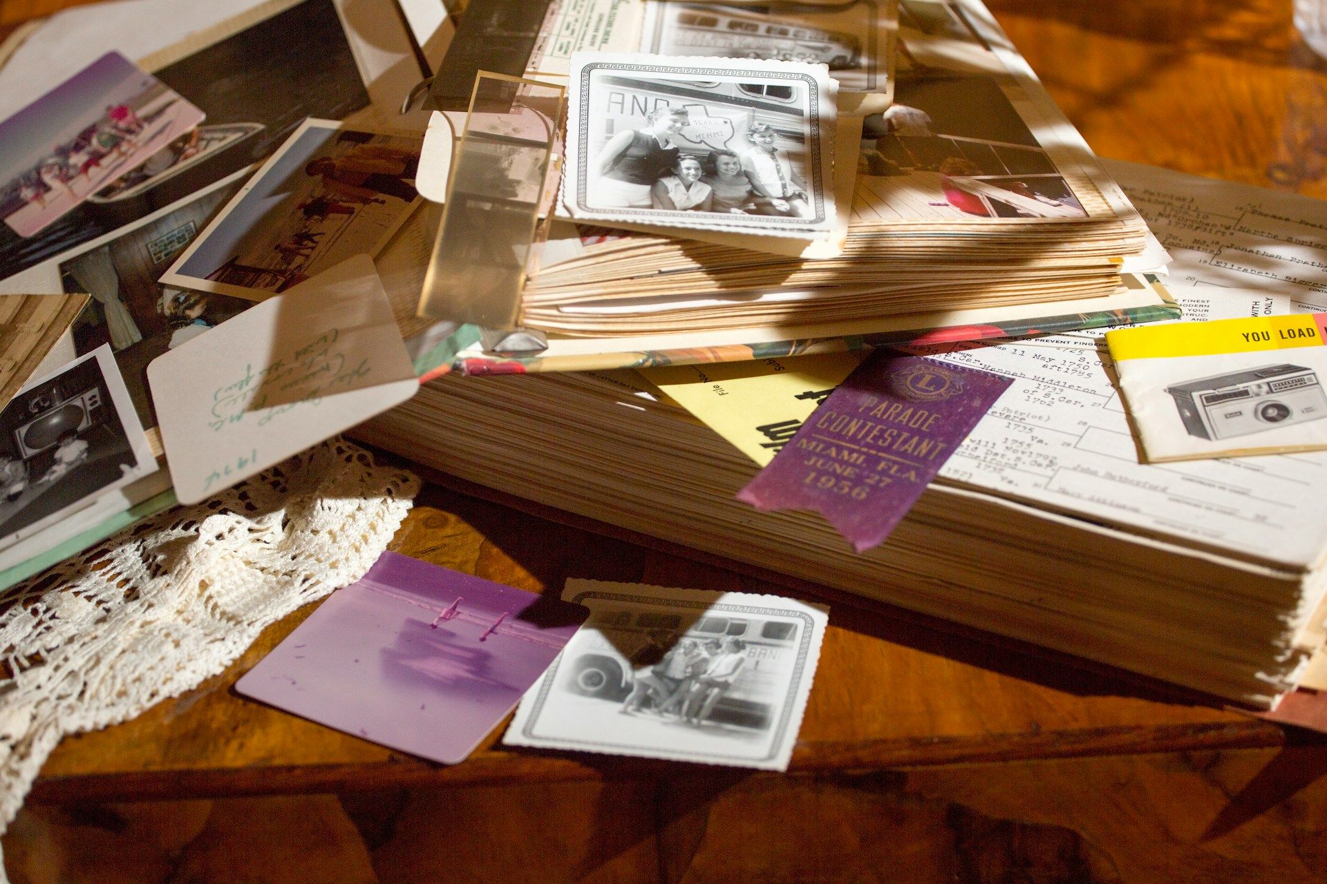 Stack of old family photographs and keepsakes spread across a table.