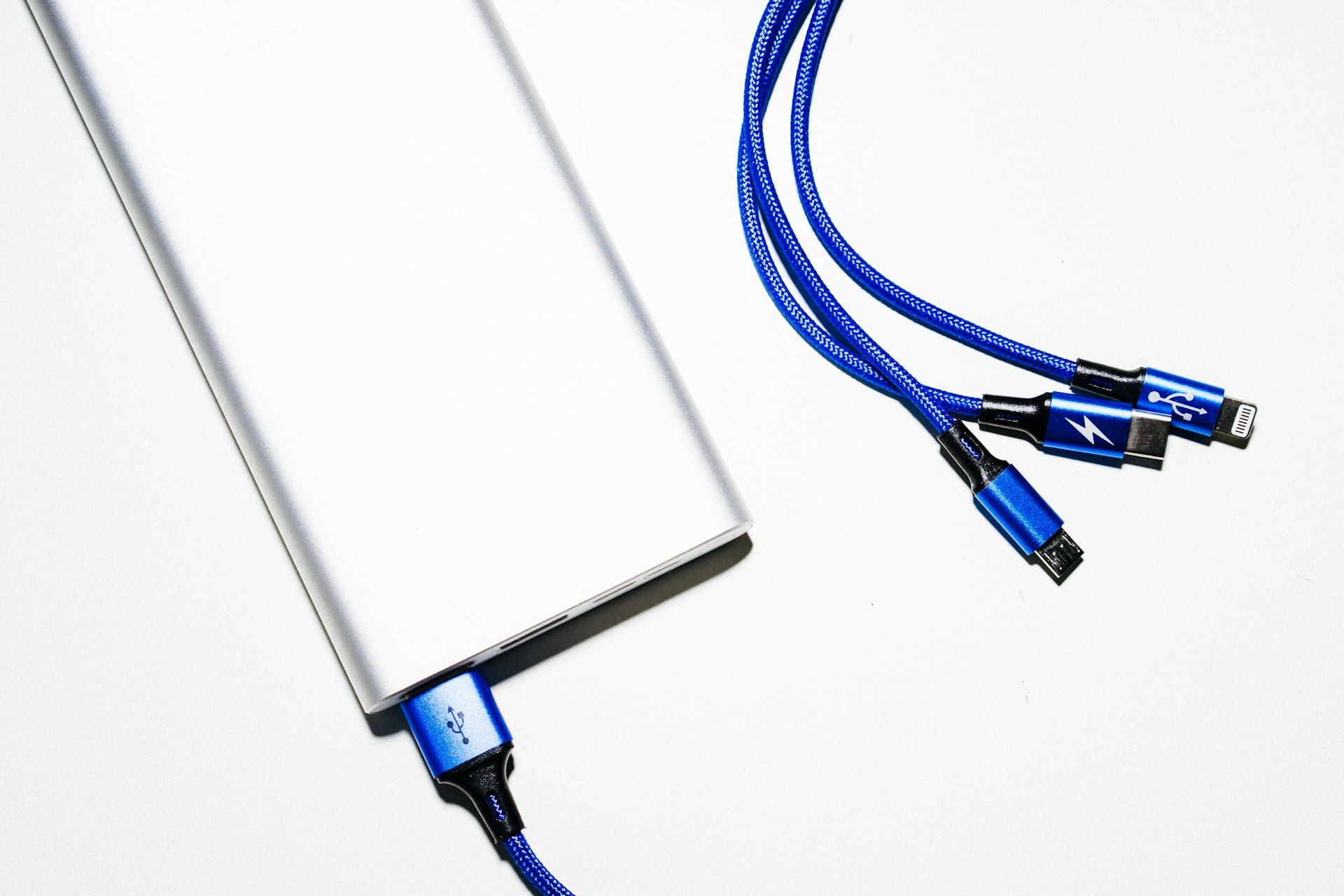 Portable power bank with a multi-tip charging cable on a white surface.