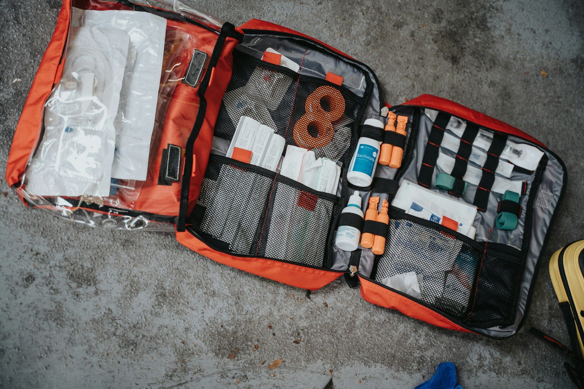 First aid kit laid out on the floor with organized medical supplies, bandages, and antiseptic.