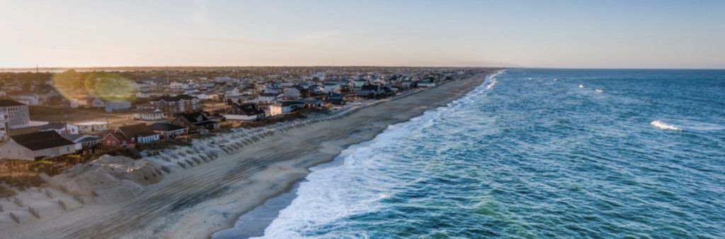 Aerial view of the Outer Banks coastline in North Carolina with ocean waves and beachfront homes.