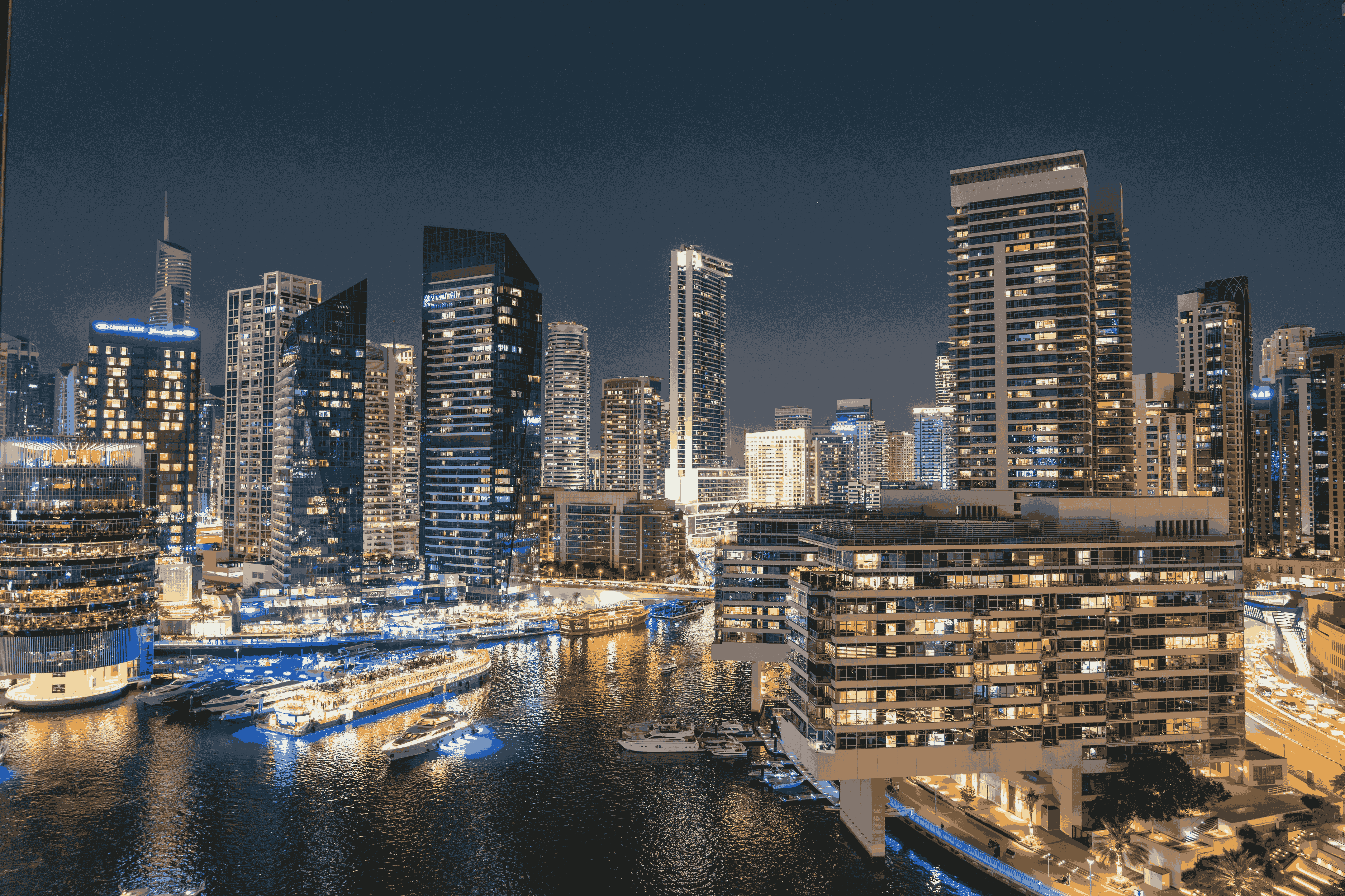 Dubai Marina skyscrapers and yachts lit up at night.